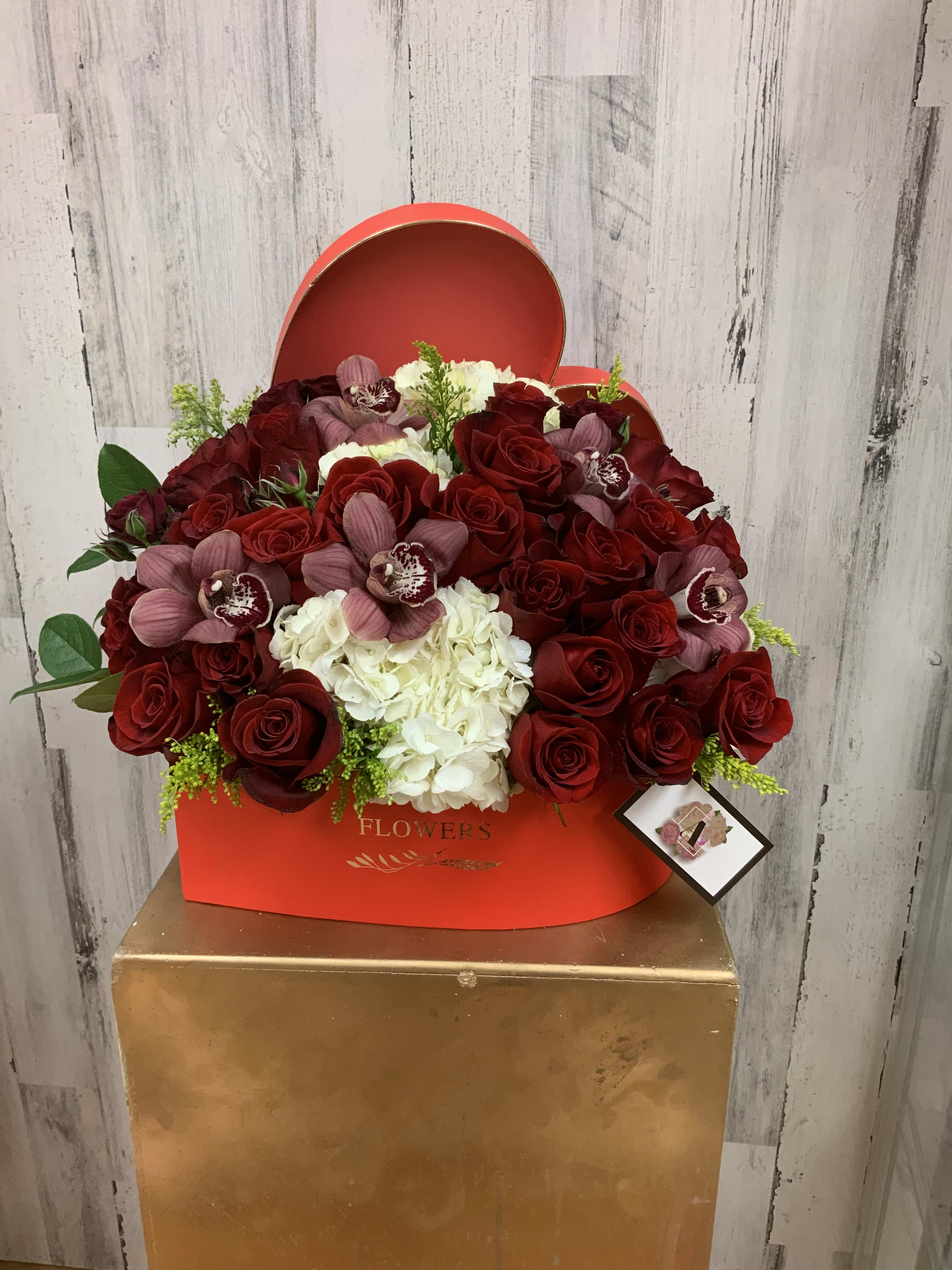 Devoted Love - Premium red roses hydrangeas and orchids in a heart shaped box. Orchid color may vary depending on availability. 