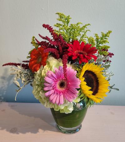 Colorful mixed bouquet in a glass vase with gerbera daisies and hydrangea
