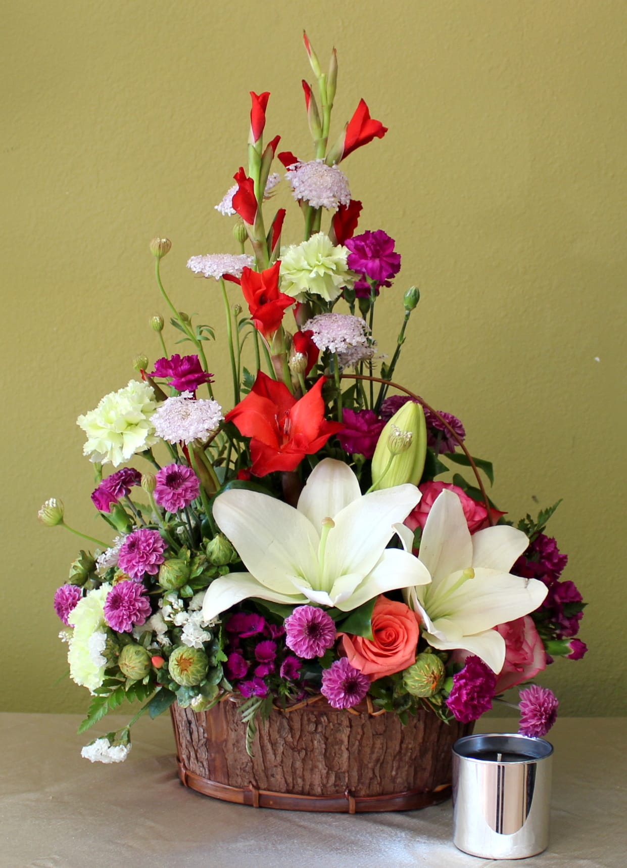 sweet inspiration  - Red Gladiolus, green  carnations purple mini carnation, orange roses and purple button mums and white Asiatic lily's in a brown basket .