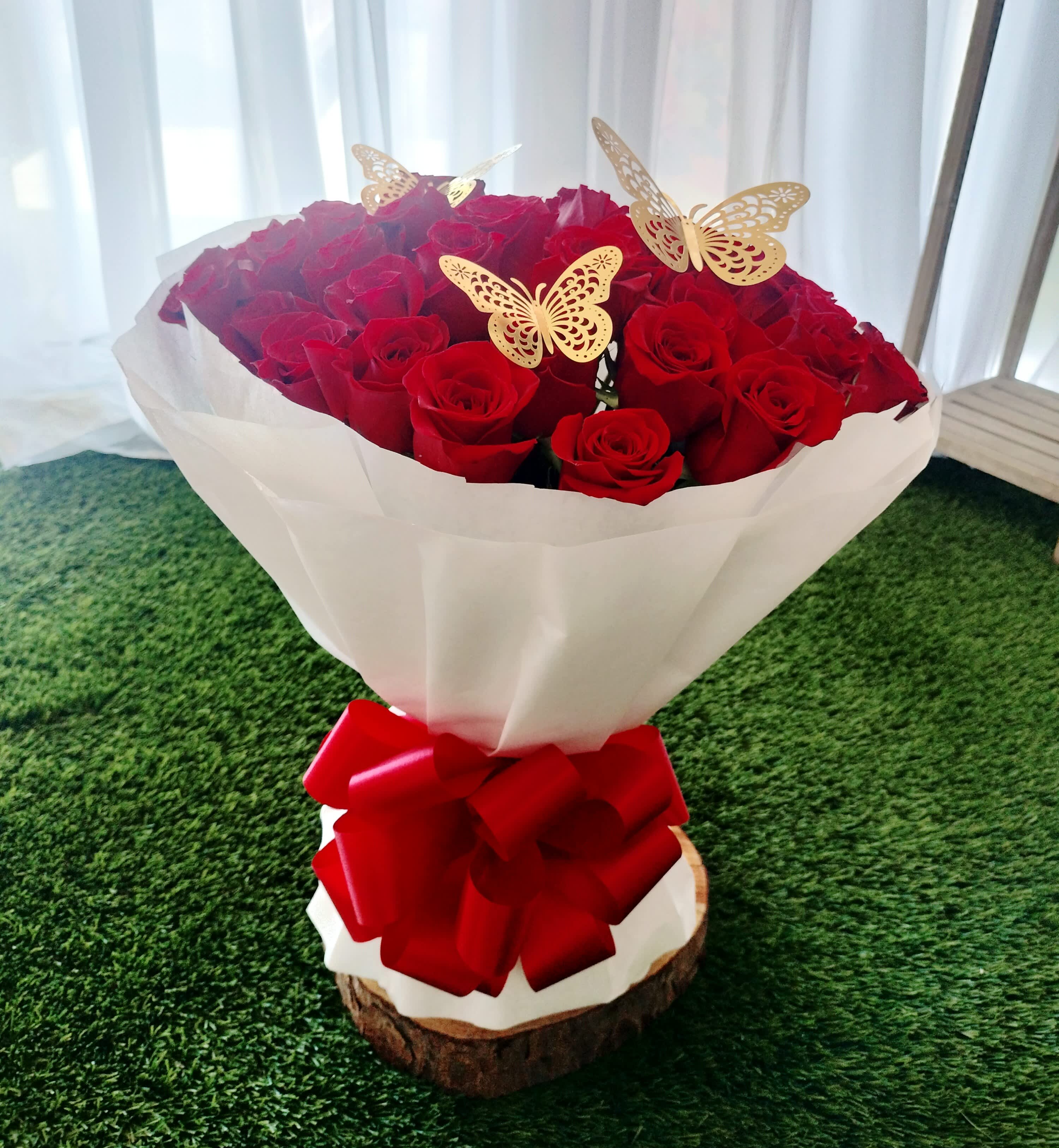 Bouquet of red roses wrapped in white paper with a red bow
