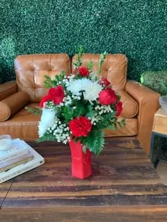 The Lovely mix  - Red ceramic vase displaying a mix of red roses, baby breath , carnations and pompoms.