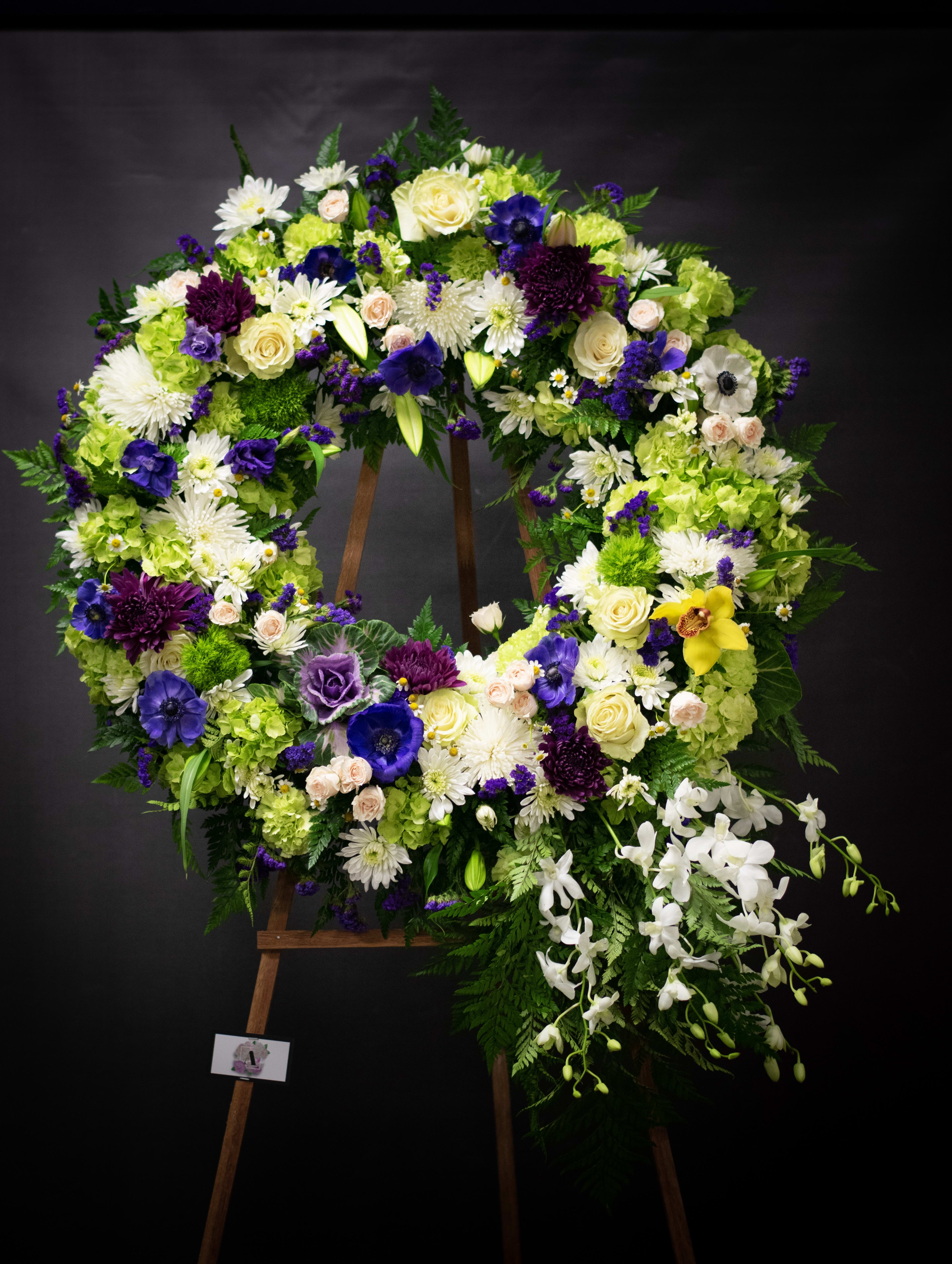 Large floral wreath on an easel with white, purple, and green flowers
