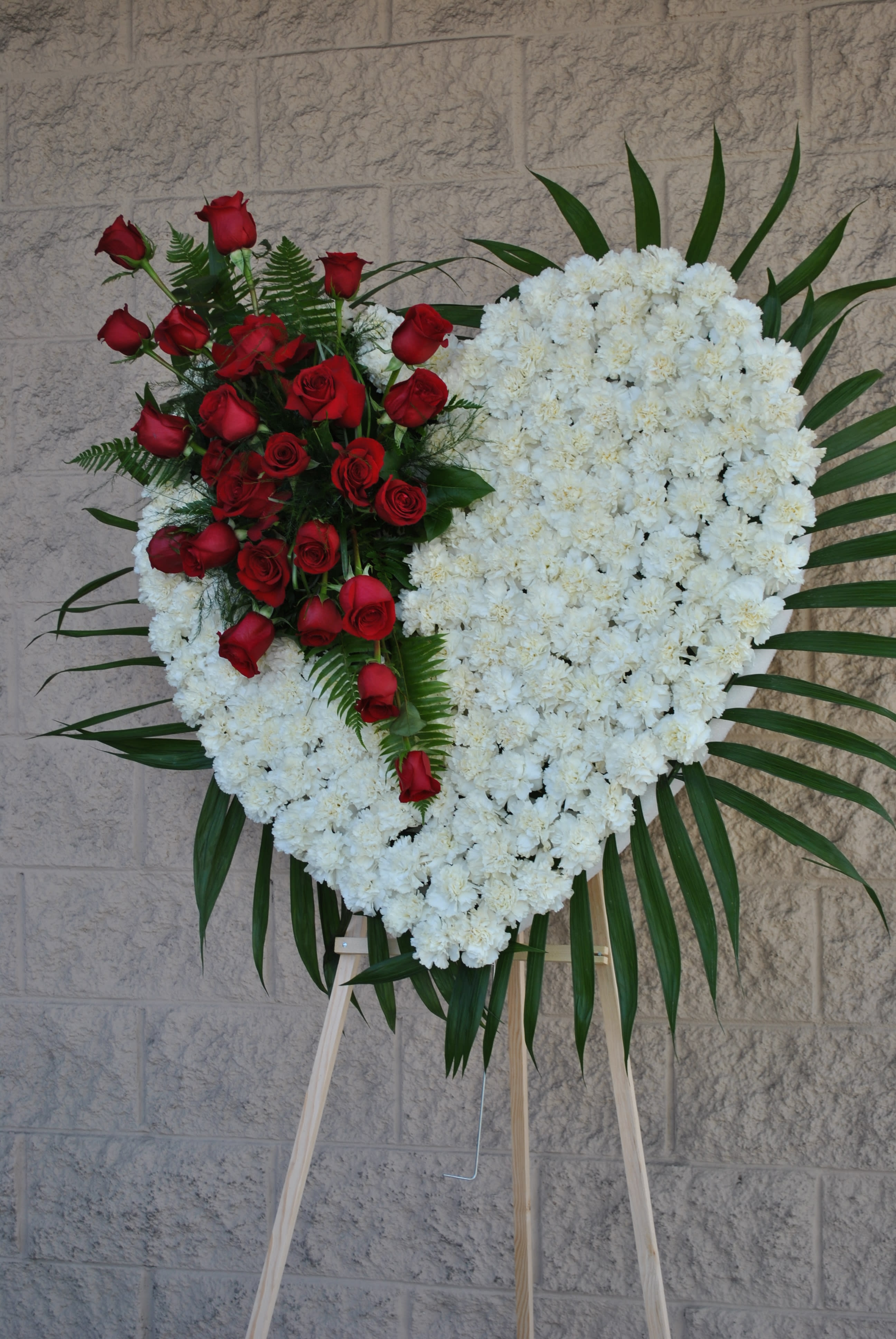 sympathy heart - full carnation heart on a standing easel made of white carnations and  cluster arrangement  made with red roses.