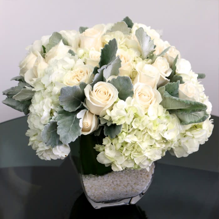 Silver Holiday Arrangement - This winter arrangement features white hydrangea, white roses, and dusty miller foliage.