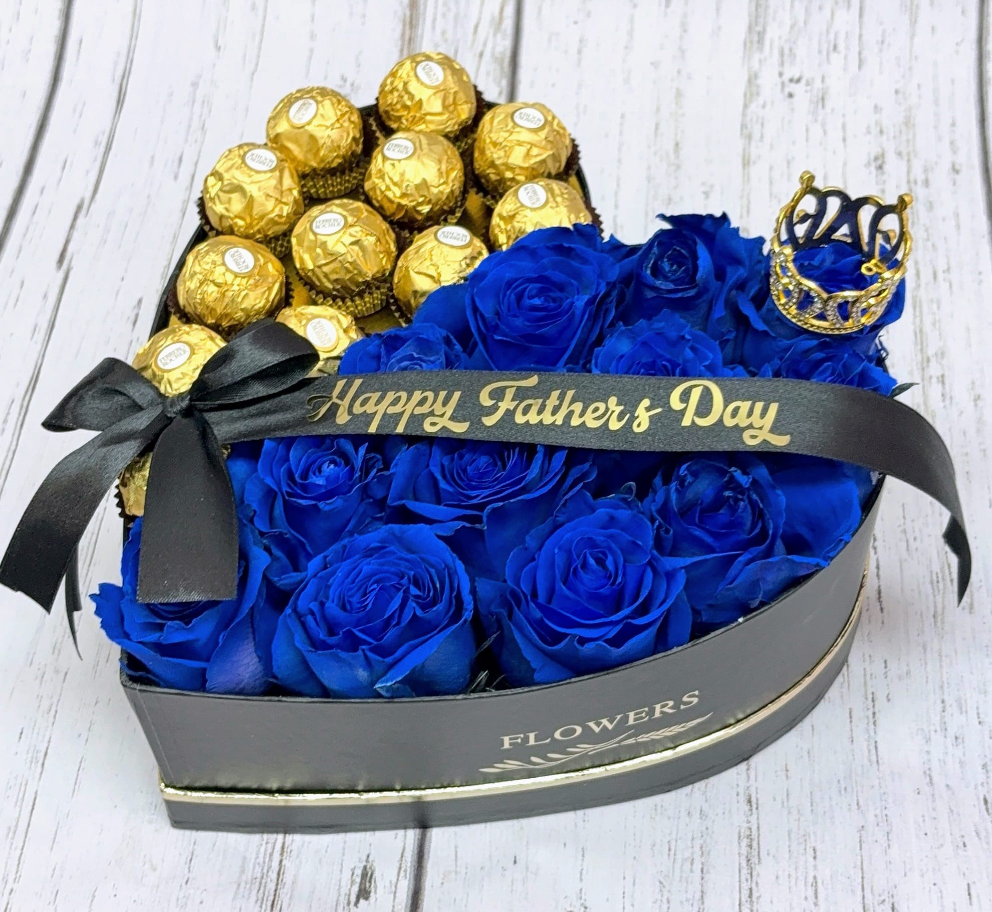 Blue roses and gold-wrapped chocolates in a heart-shaped gift box