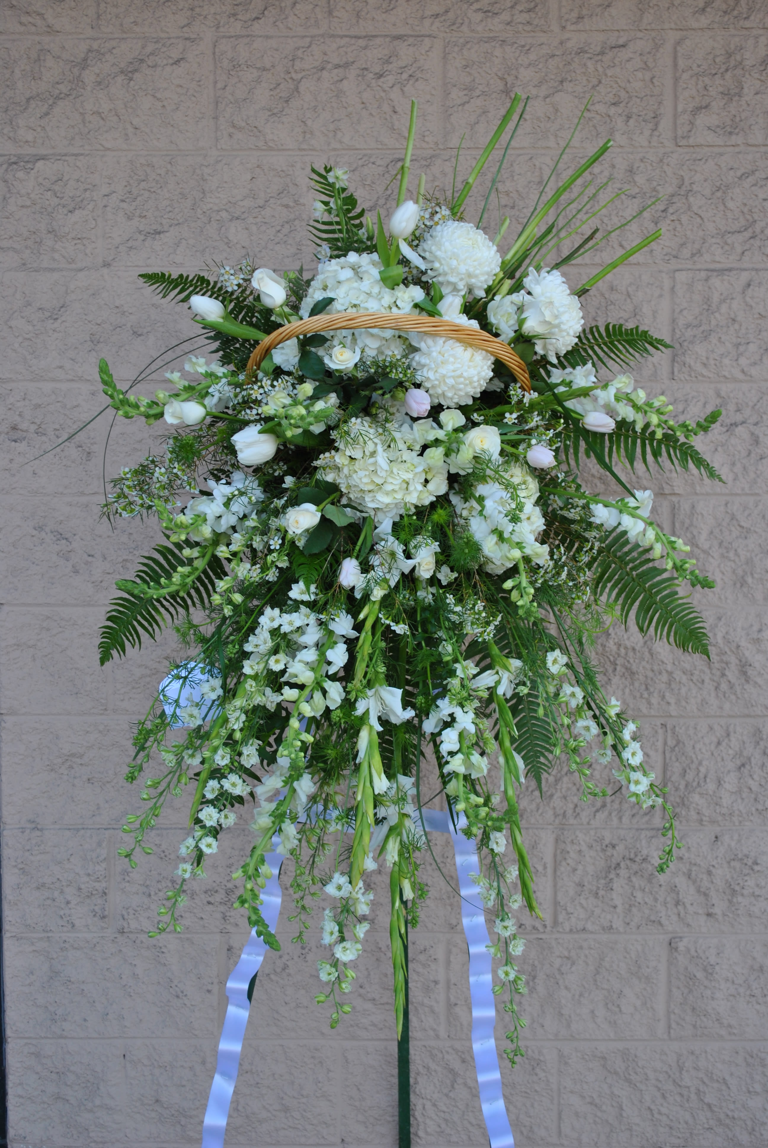 White Sympathy Cascade - A grand display of white hydrangea, dephinium, chrysanthimum, snap dragons, gladiolas, tulips, and tropical foliage.