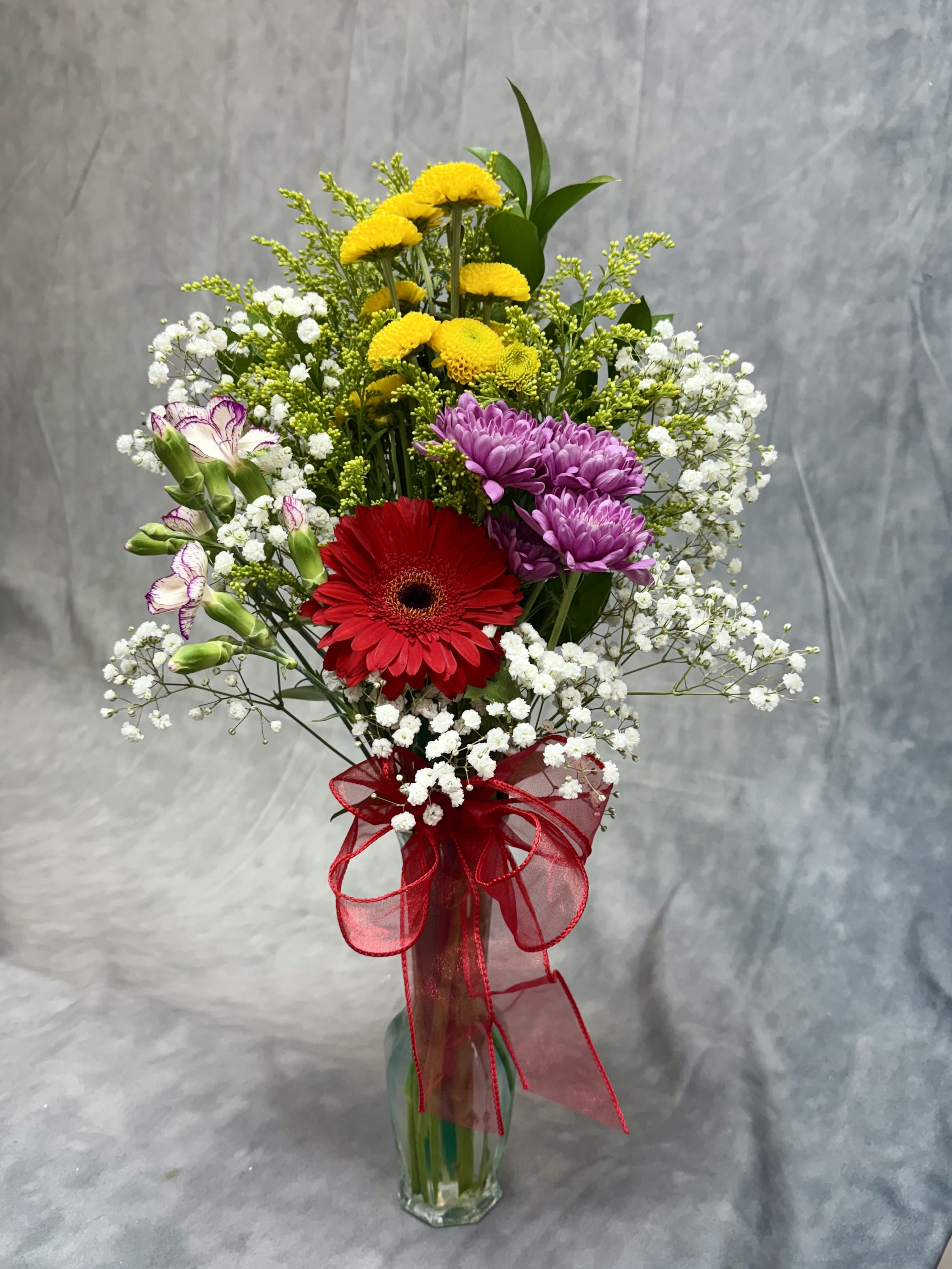Mixed bouquet in a glass vase with red, purple, and yellow flowers
