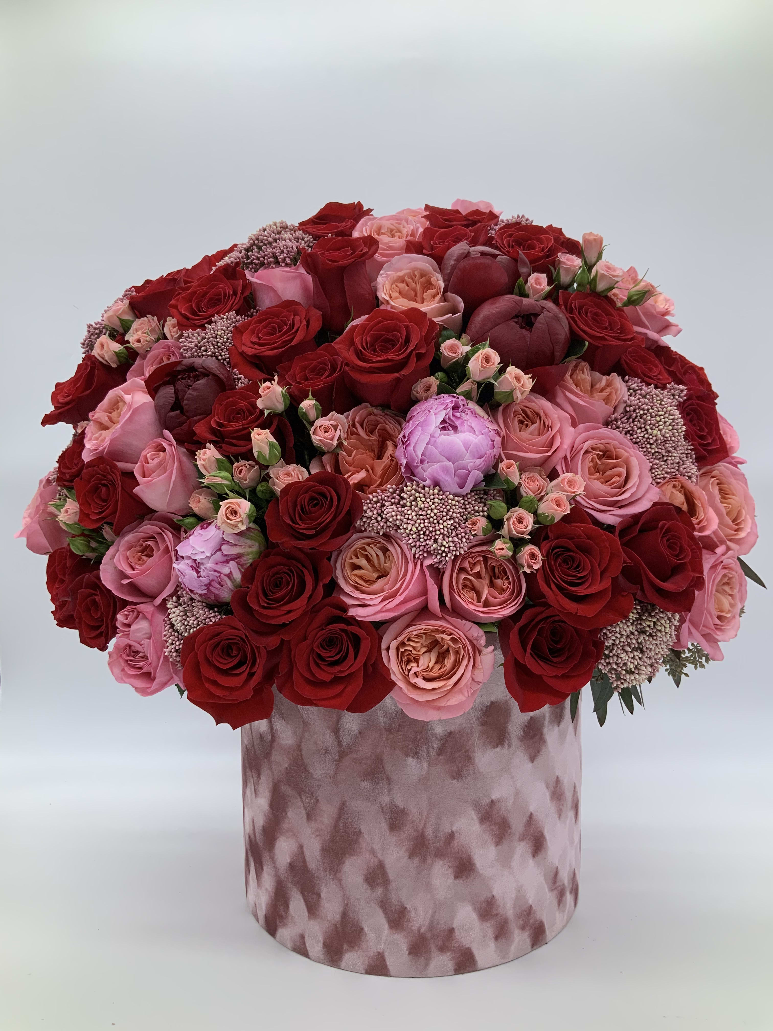 Burgundy Elegance byAmore Luxury Collection  - Beautiful burgundy’s and shades of pink combined in a velvety hat box make up this gorgeous floral arrangement. Includes peonies,roses, spray roses, and other accent flowers.  Please not that some flowers are seasonal and flowers will be replaced to value if not available. A photo will be sent for approval before delivery. Please let us know of any changes you would like in the special instructions section. 