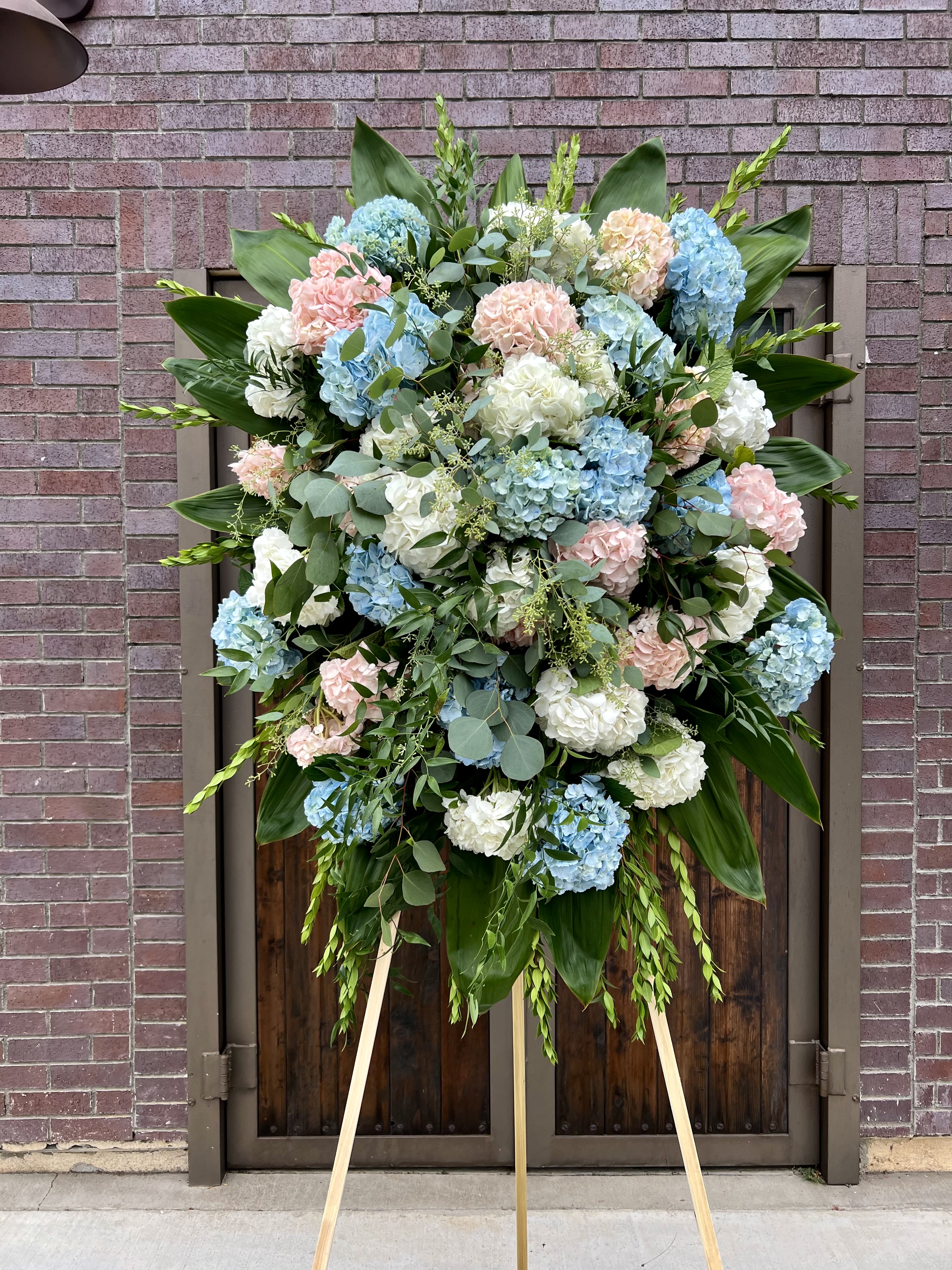 Large standing spray of blue, white, and pink hydrangeas