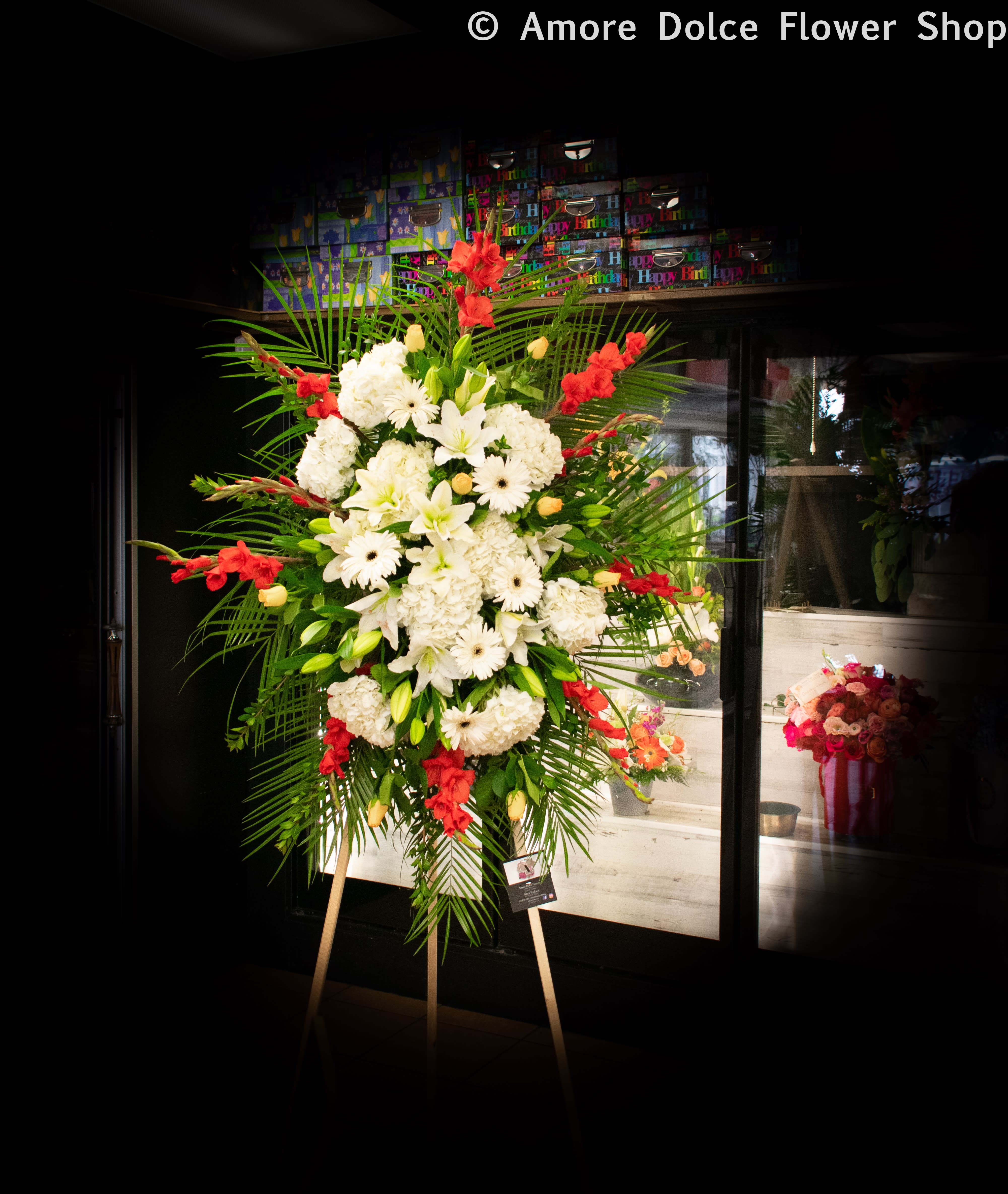 Large standing floral spray with white blooms and red accents on an easel