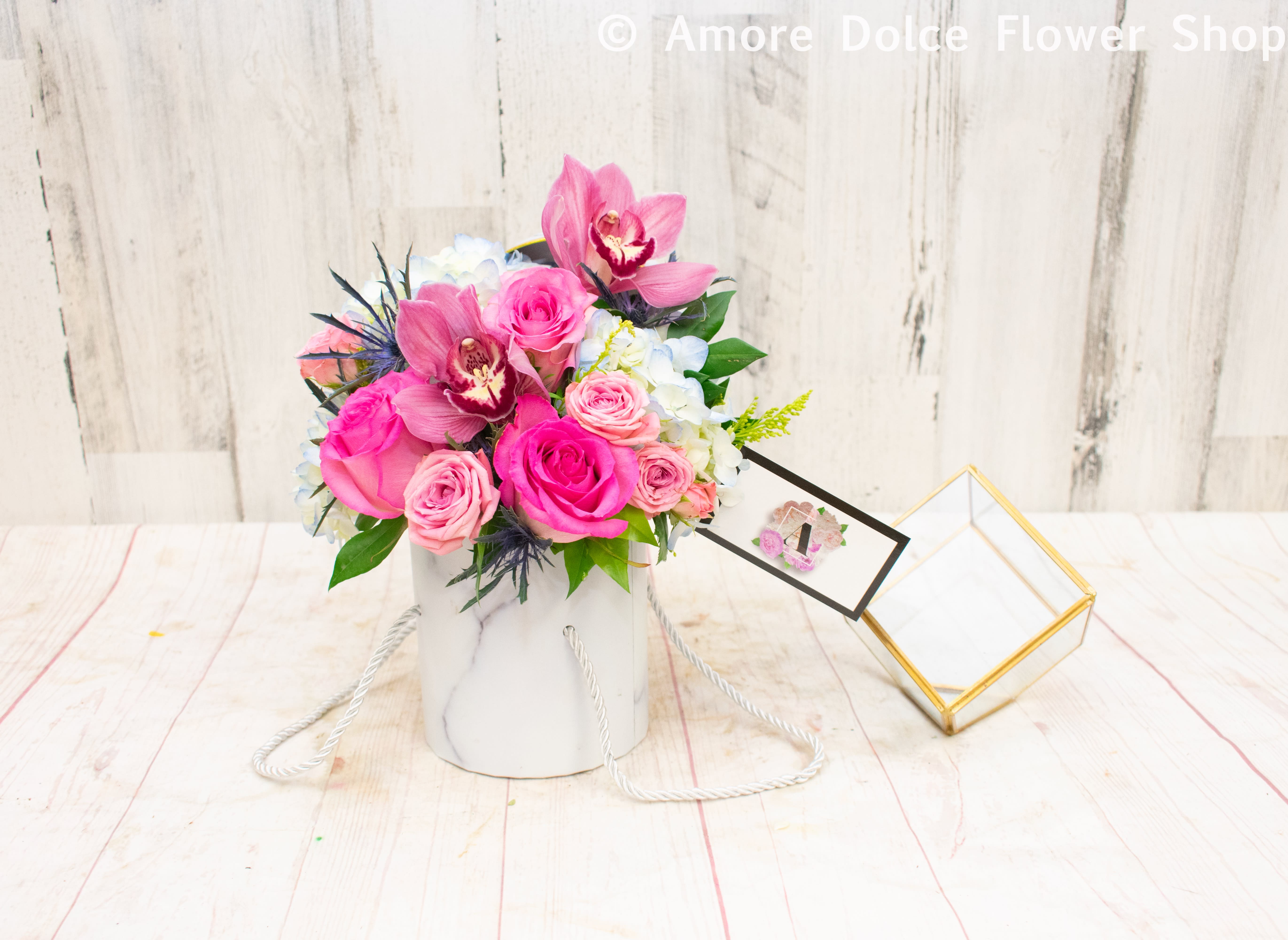Mini Hat Box  - Don’t let the size fool you — this petite arrangement makes a big impression. Designed in a compact hatbox, it’s perfect for brightening someone’s day with a sweet, stylish gesture. Featuring a lovely mix of seasonal blooms like roses, orchids, and hydrangeas, this arrangement brings elegance to any moment.  Please note: Flower varieties and hatbox styles may vary based on seasonal availability. If you have specific color or flower preferences, feel free to leave a note in the special instructions section and we’ll do our best to accommodate your request.  