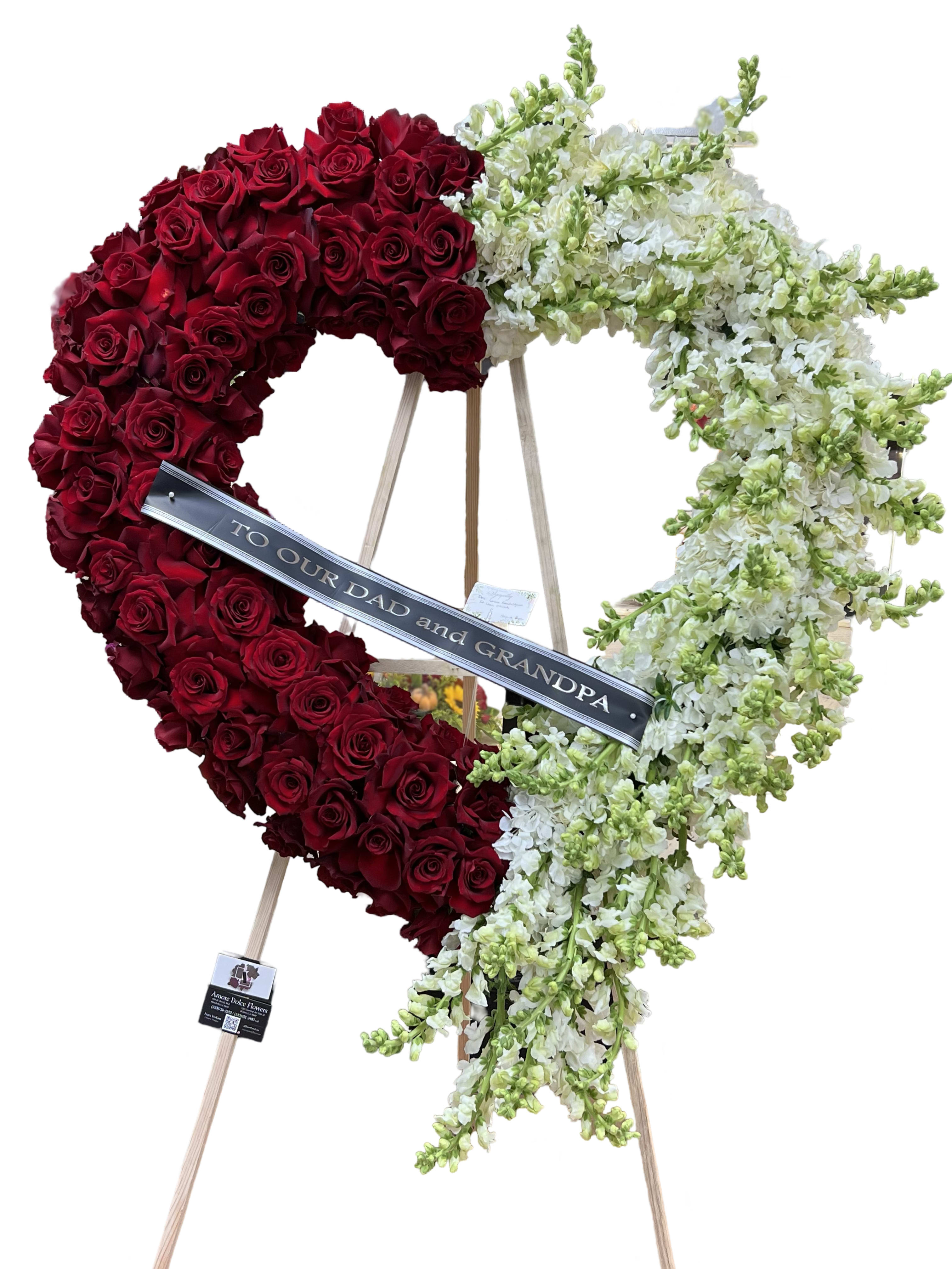 Heart-shaped floral tribute of red roses and white flowers on an easel