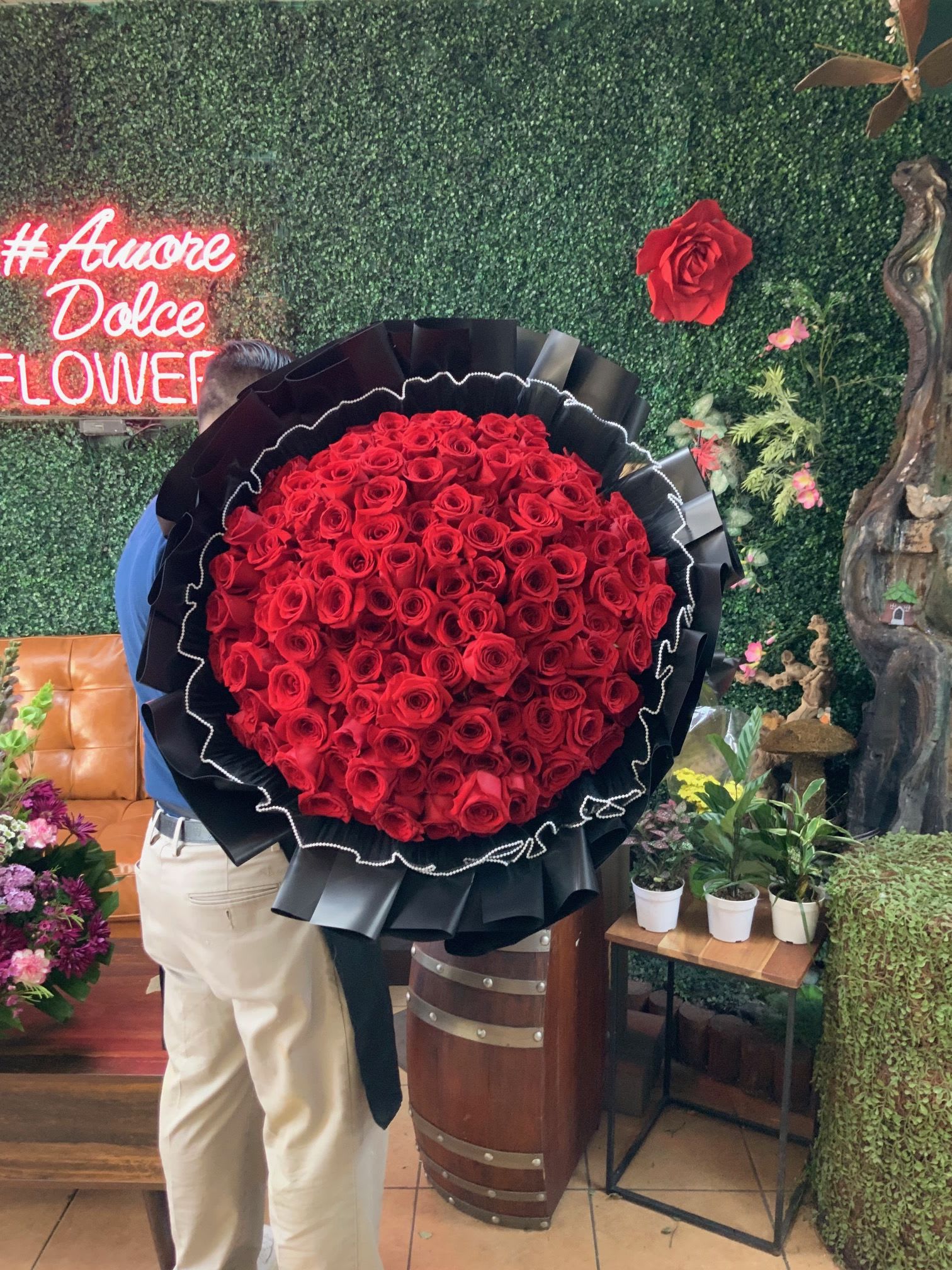 Bloom Baby!  - Luxury 100 Red Roses Bouquet – Black Wrap with Pearl Accents  Make a bold and unforgettable statement with our stunning 100 Long-Stem Red Roses Bouquet. Elegantly wrapped in black with delicate pearl-accented tulle trim, this bouquet exudes sophistication, romance, and timeless beauty.  Bouquet Features:   100 Premium Long-Stem Red Roses – Fresh, vibrant, and hand-selected for quality.   Elegant Black Wrapping – A modern and luxurious presentation.   Black Tulle Trim with Pearl Accents – A delicate touch of elegance and sophistication.   Grand &amp; Show-Stopping – The ultimate bouquet for making a lasting impression.   Perfect for:  	•	Romantic surprises &amp; anniversaries  	•	Valentine’s Day &amp; proposals  	•	Luxury gifts &amp; special celebrations  	•	Making an unforgettable impression   Handcrafted with care – Each bouquet is carefully arranged for the perfect presentation.   Limited Availability! Order in advance to ensure delivery.