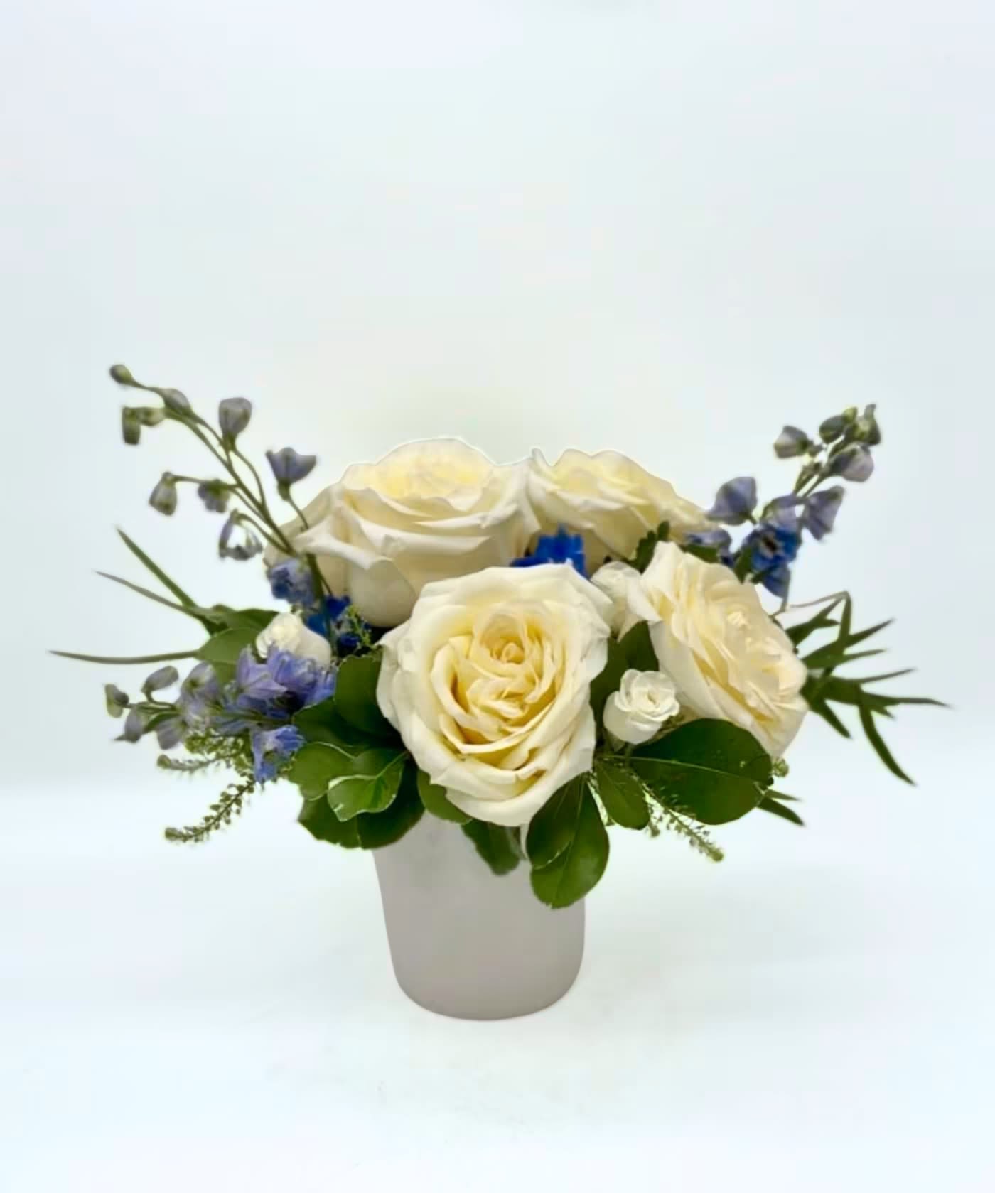 Candlelit Tides - This modern display highlights 'Candlelight' garden roses (our owner's favorite variety), accented by blue delphinium and white spray roses. The natural pastels are reminiscent of the Atlantic coast beach scenes and relaxing times in the sun. Perfect for anniversaries, congratulations, just because, or to put on your own table! Two sizes to choose from.