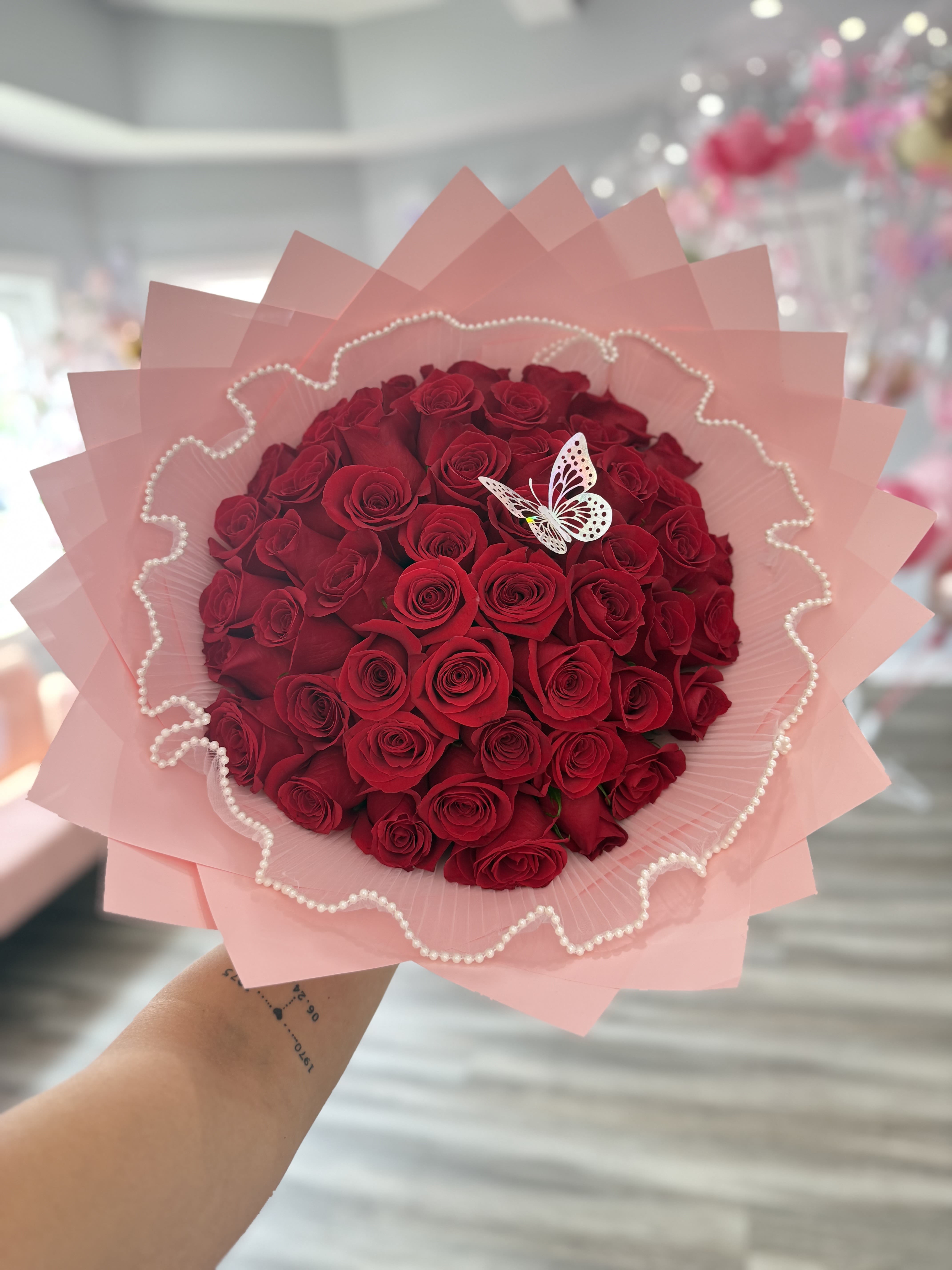 Bouquet of red roses wrapped in pink paper with a butterfly decoration