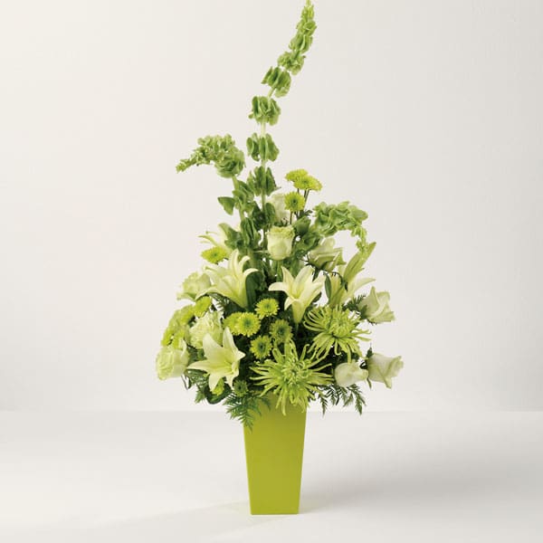 Tall green and white floral arrangement in a lime vase