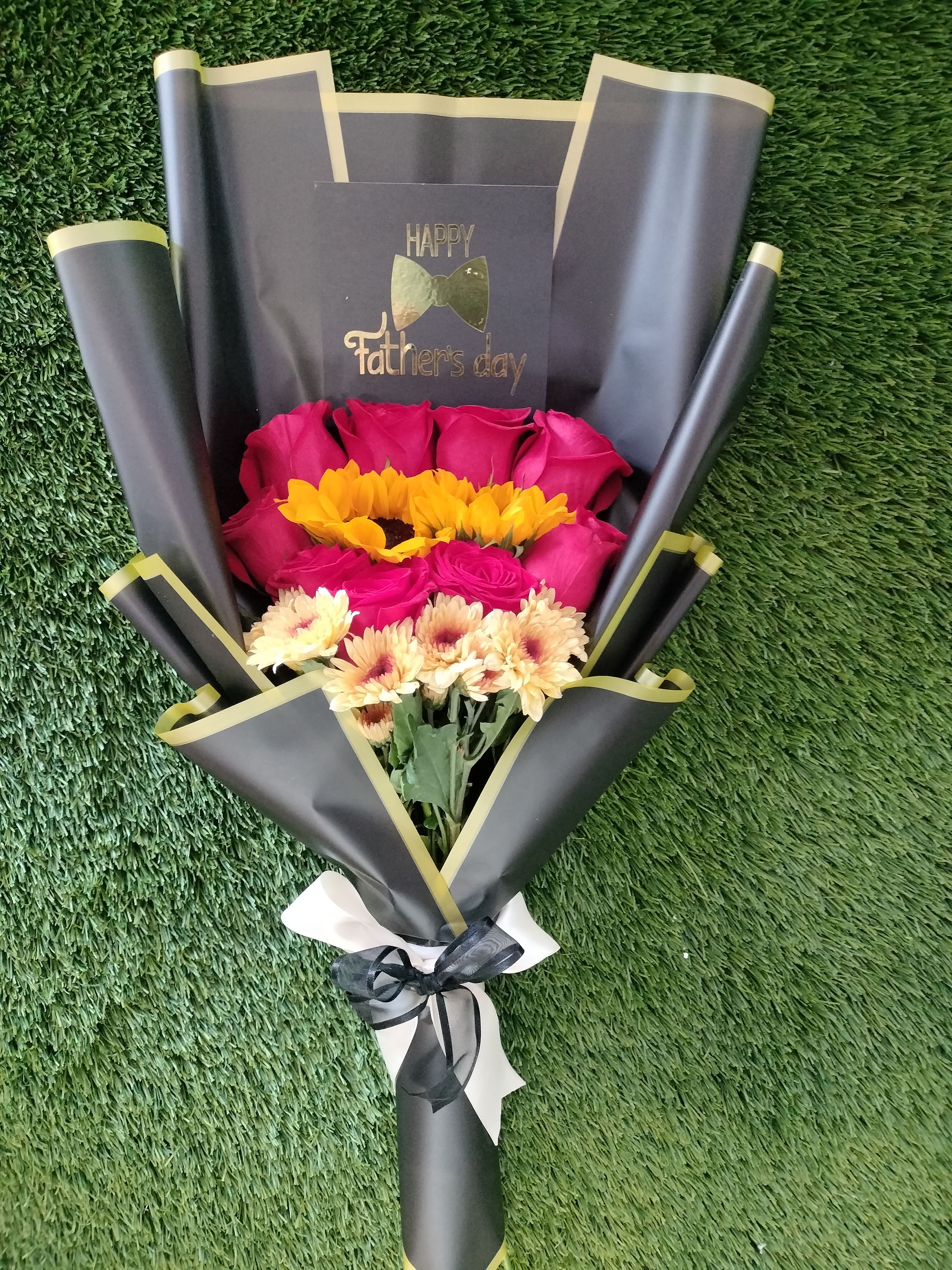Bouquet of pink roses and yellow daisies wrapped in black paper