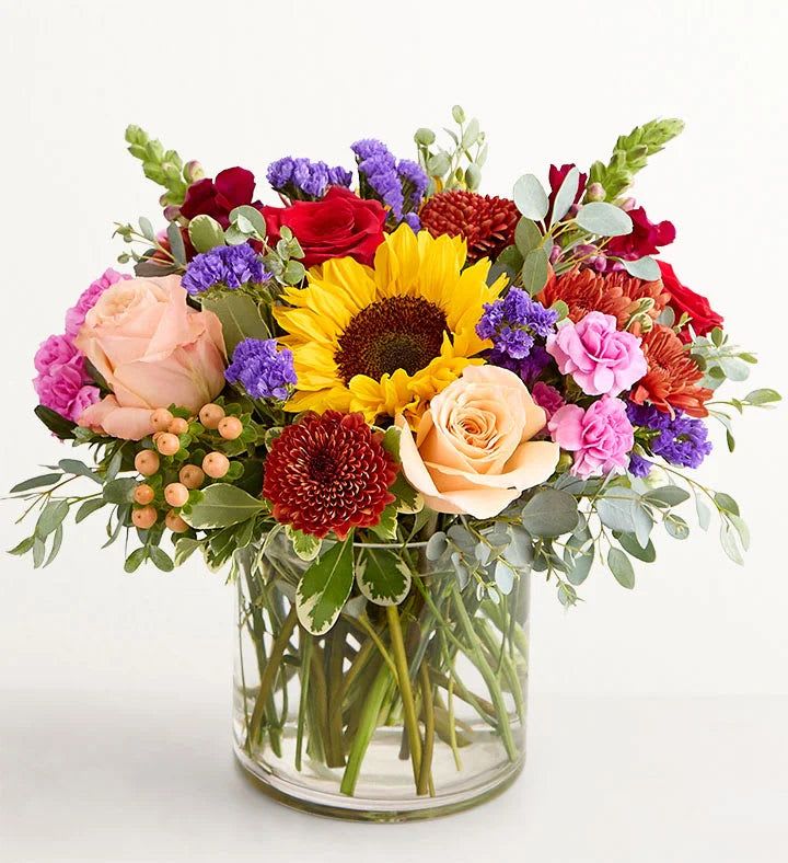 Mixed bouquet with sunflowers, roses, and chrysanthemums in a glass vase