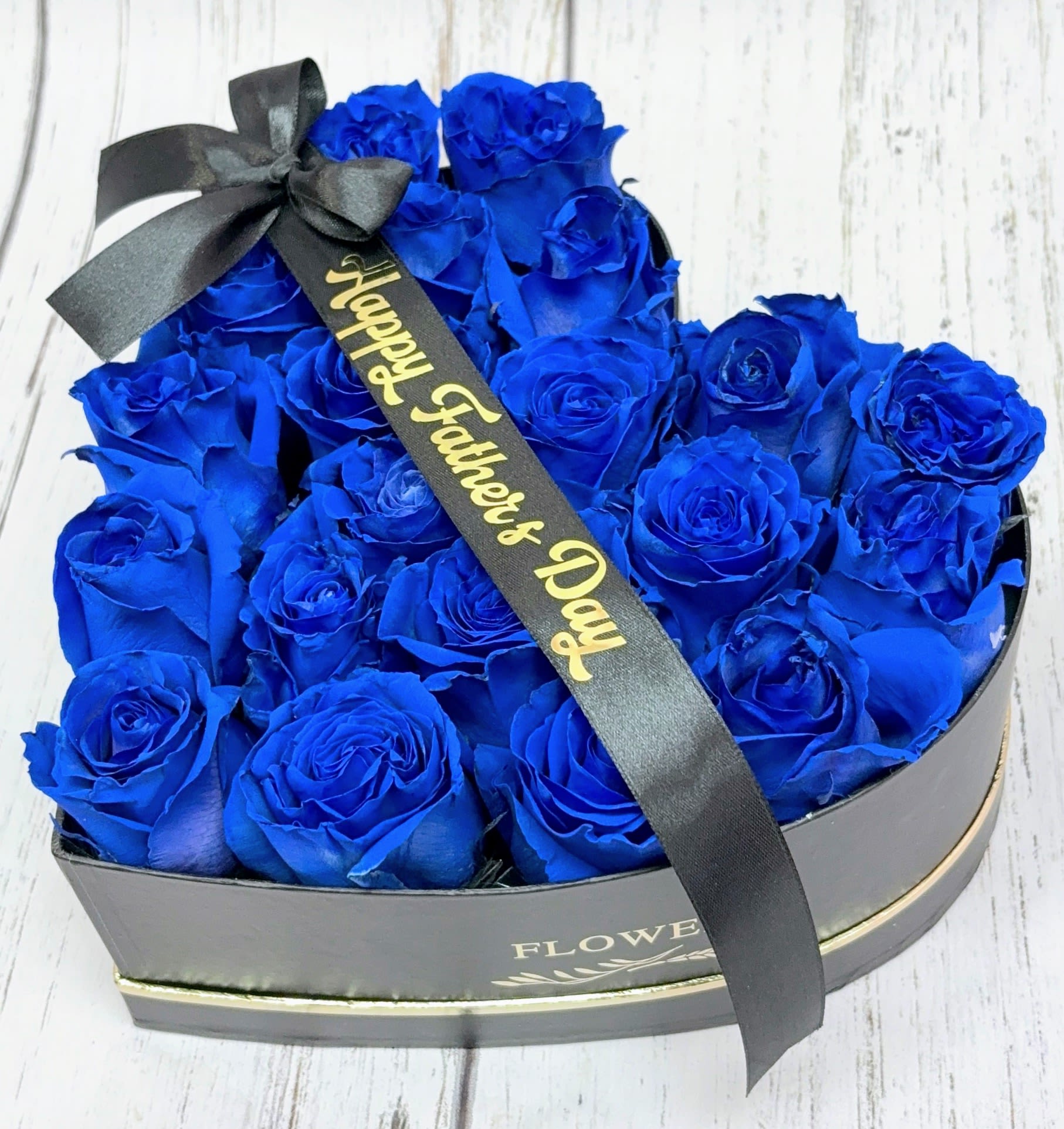 Heart-shaped box of blue roses with a black ribbon