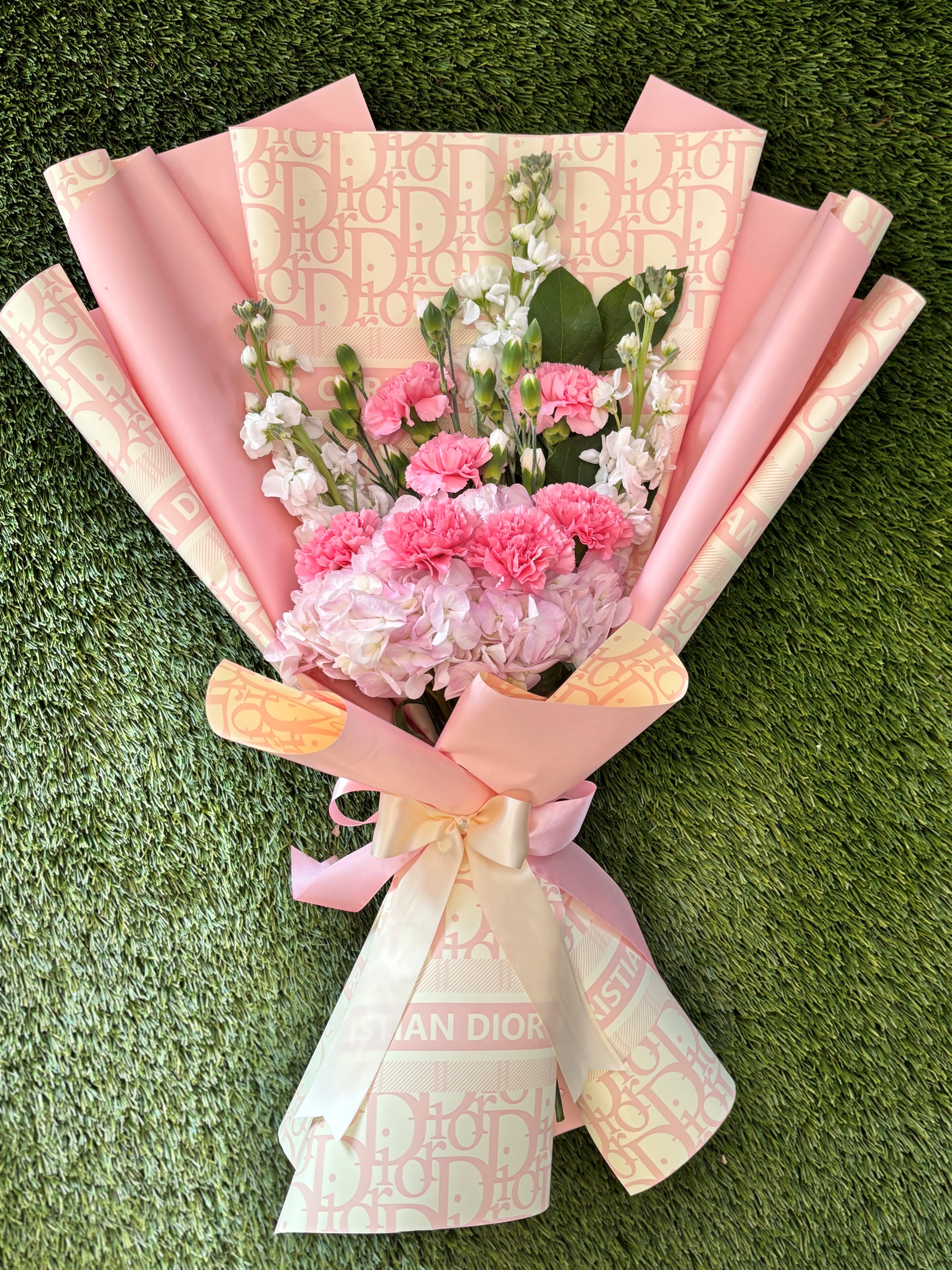 Pink and white bouquet with carnations and hydrangea wrapped in patterned paper
