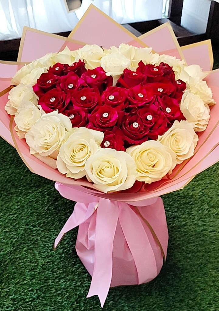 Heart-shaped bouquet of red and white roses wrapped in pink paper
