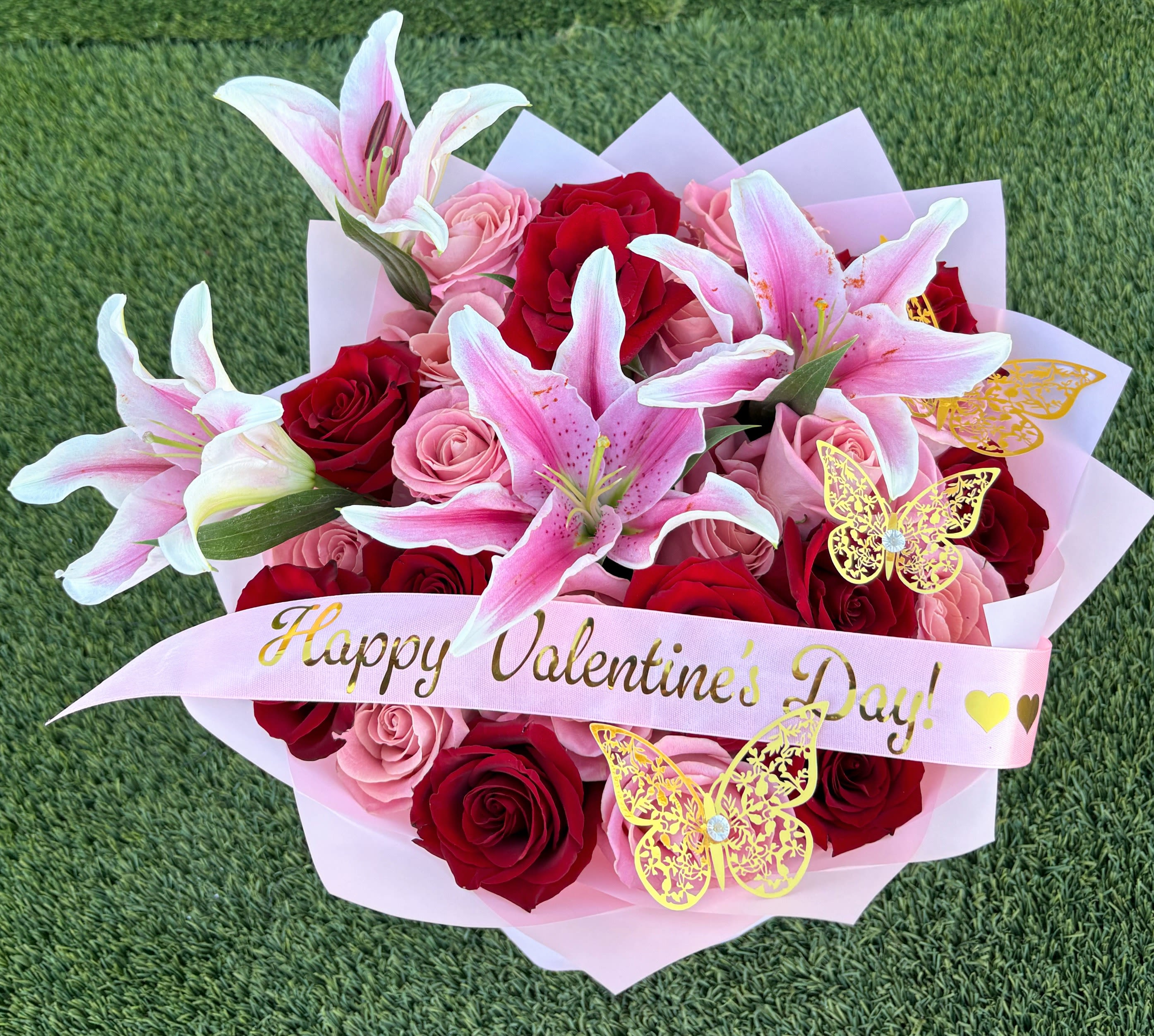 Bouquet of red and pink roses with pink lilies and a Valentine ribbon