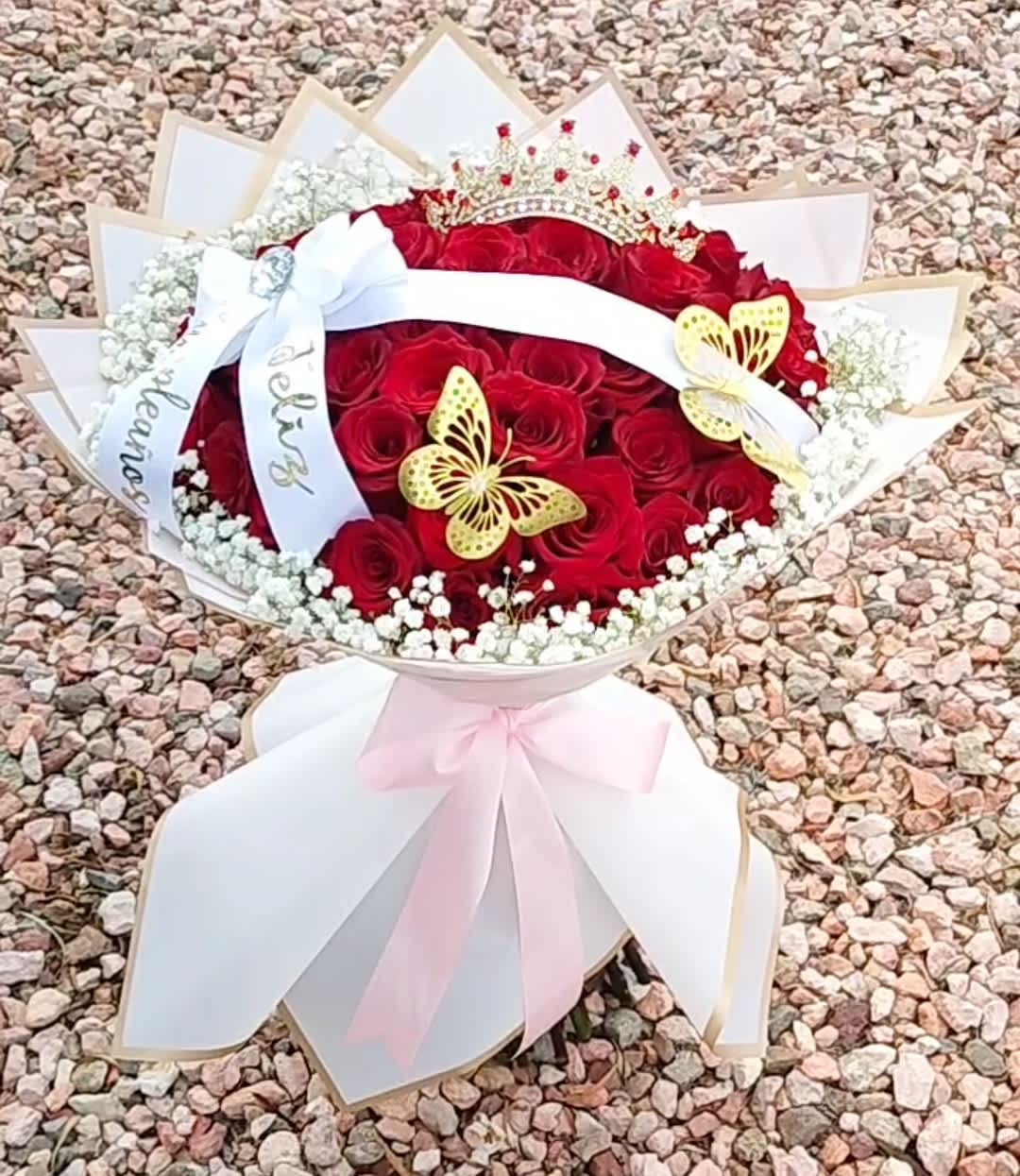 Red rose bouquet with white ribbon, butterflies, and a crown topper