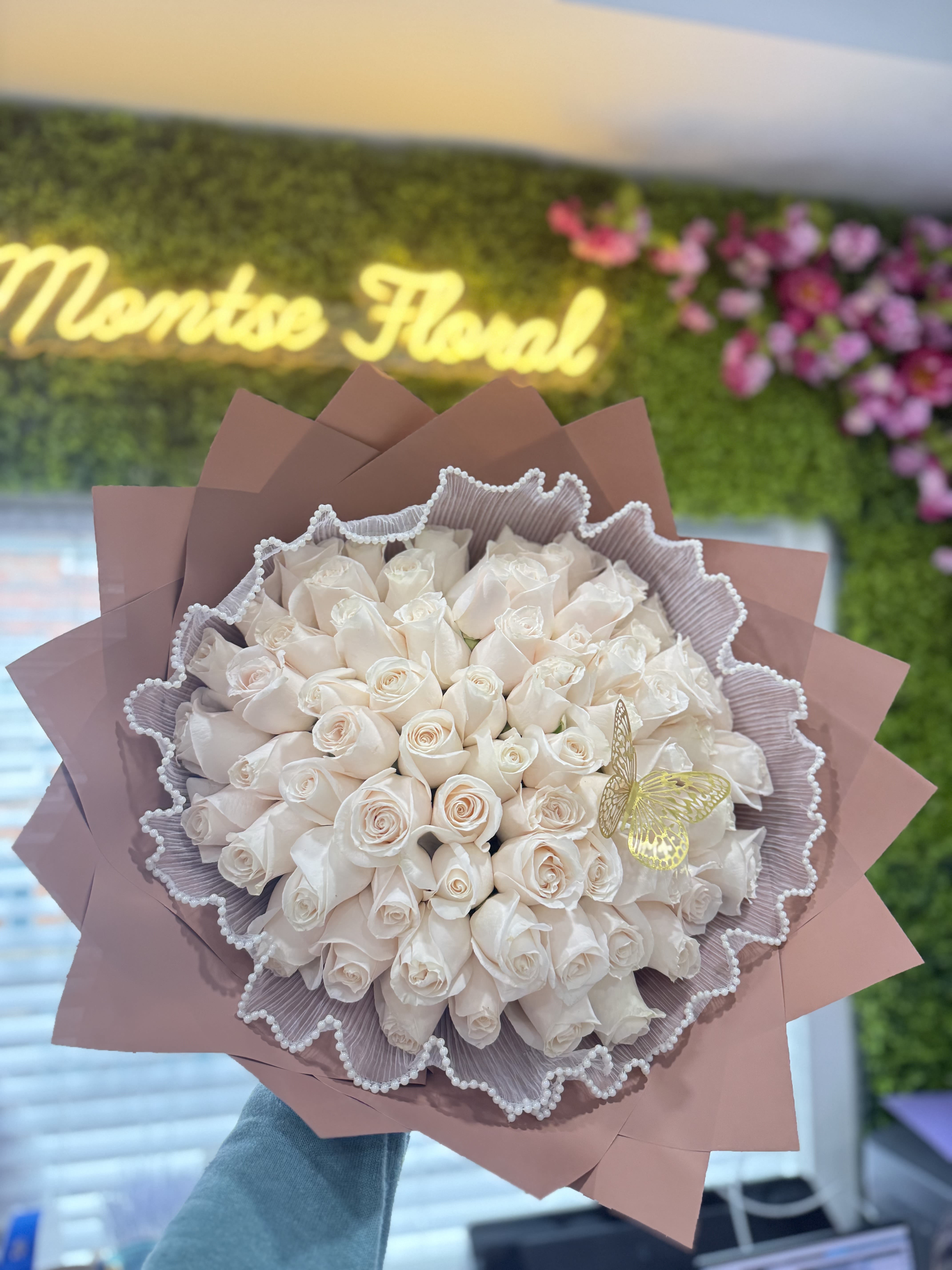 Bouquet of pale cream roses wrapped in pink paper