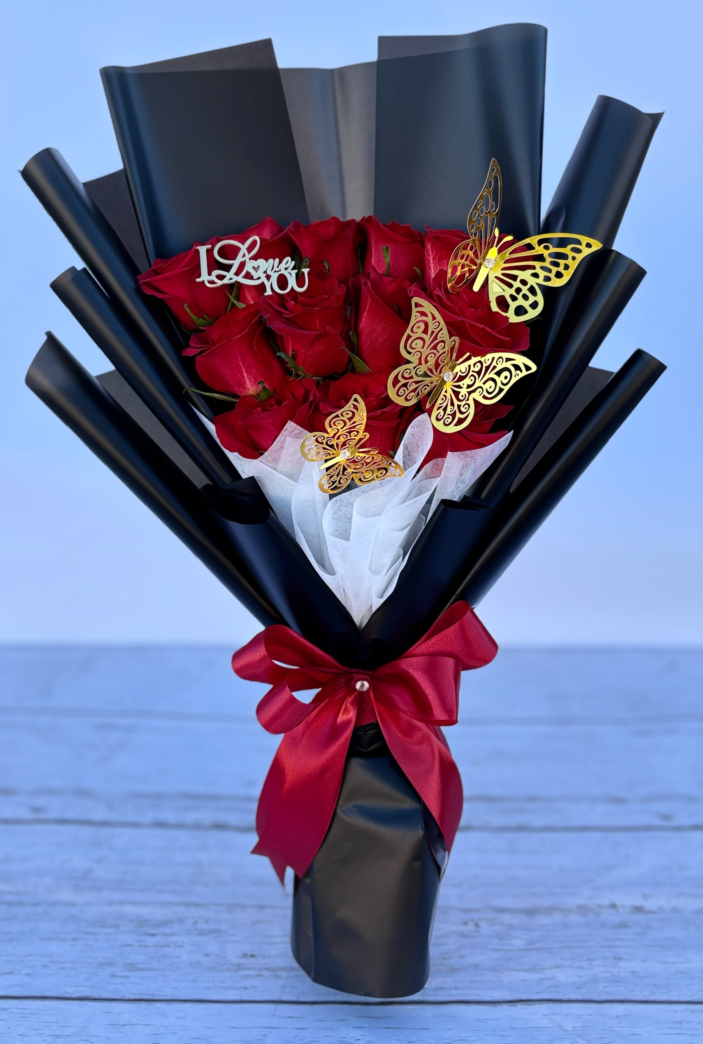 Bouquet of red roses wrapped in black paper with a red ribbon
