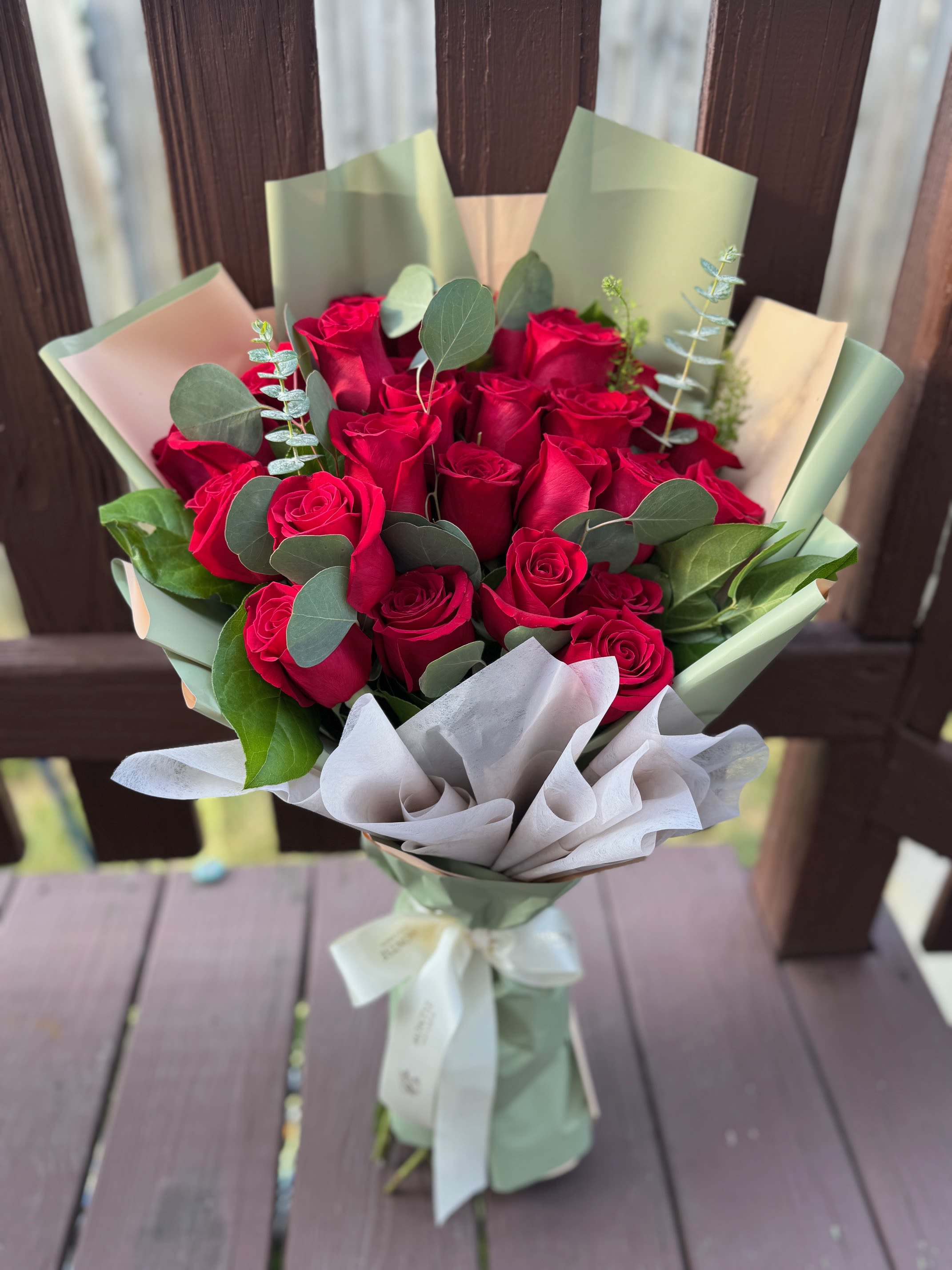 Bouquet of red roses wrapped in pale green and white paper