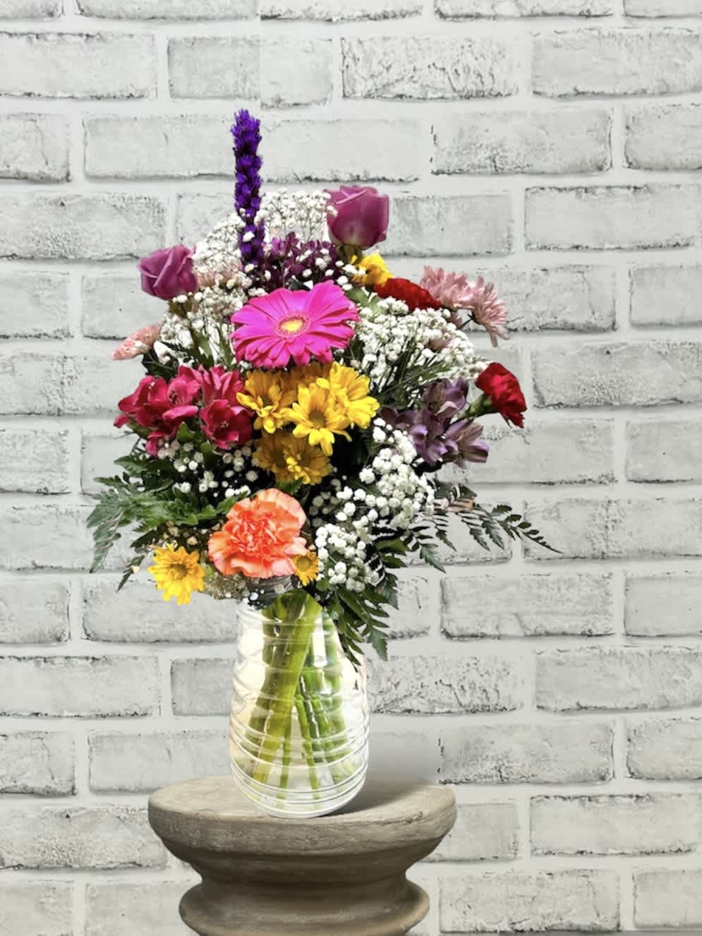 Mixed bouquet in a clear glass vase with pink, yellow, purple, and white flowers
