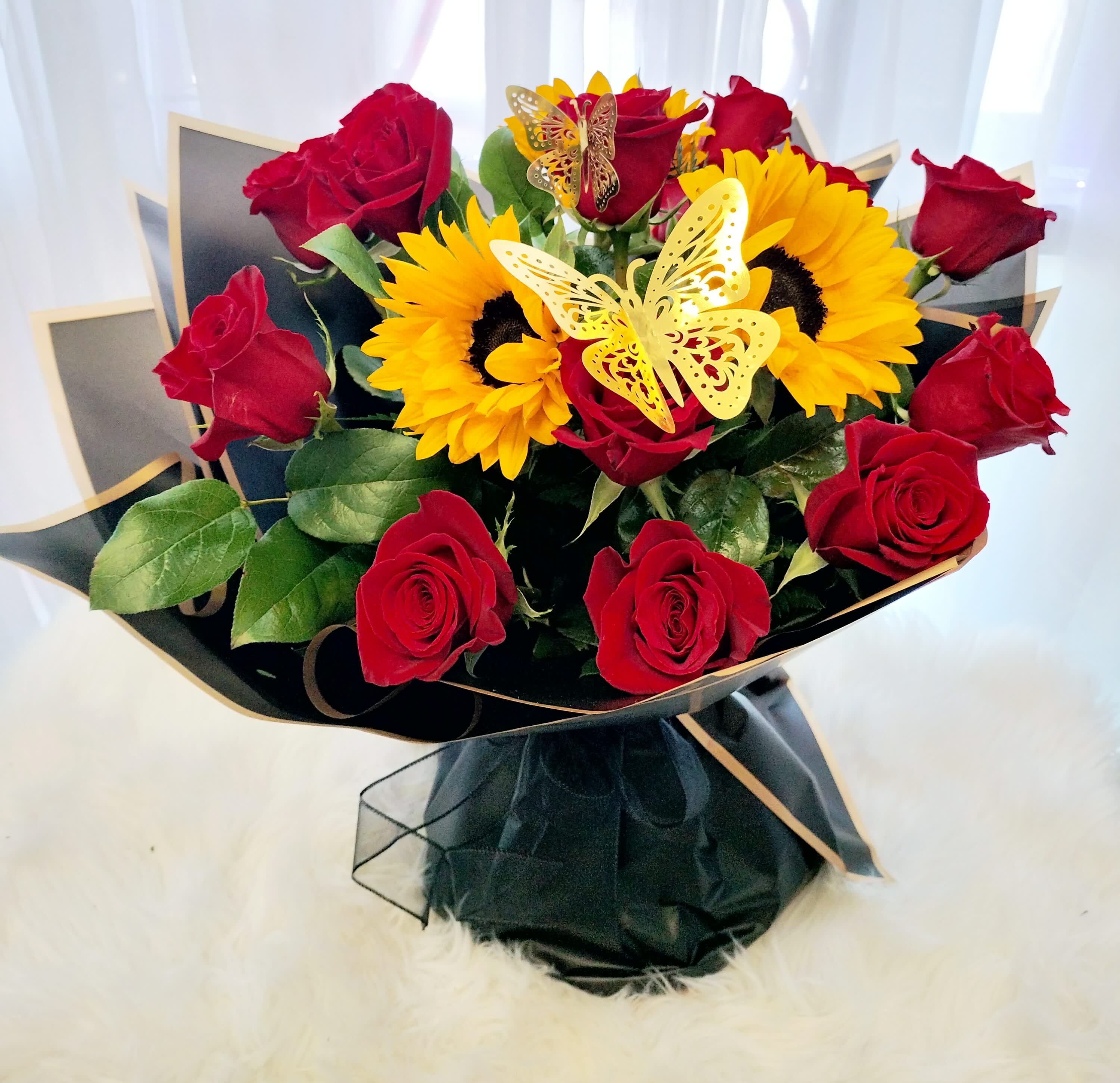 Bouquet of red roses and yellow sunflowers with butterfly picks