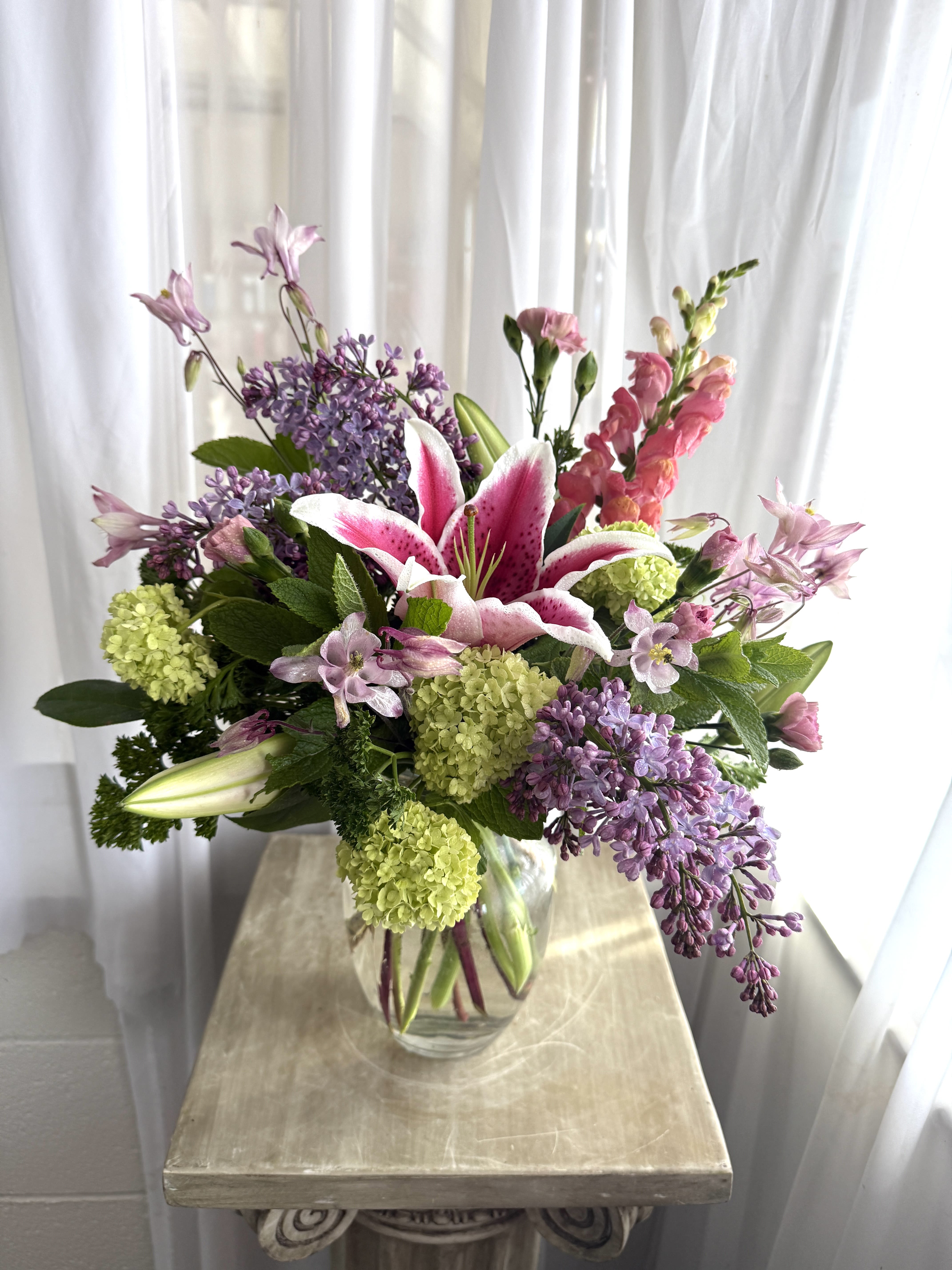 Lilies and Lilac - A lively mix of lilies, lilac, roses, and other interesting fillers.  As always, designer may substitute vase or flowers based on what we have in stock.  Call to find out what we have available.