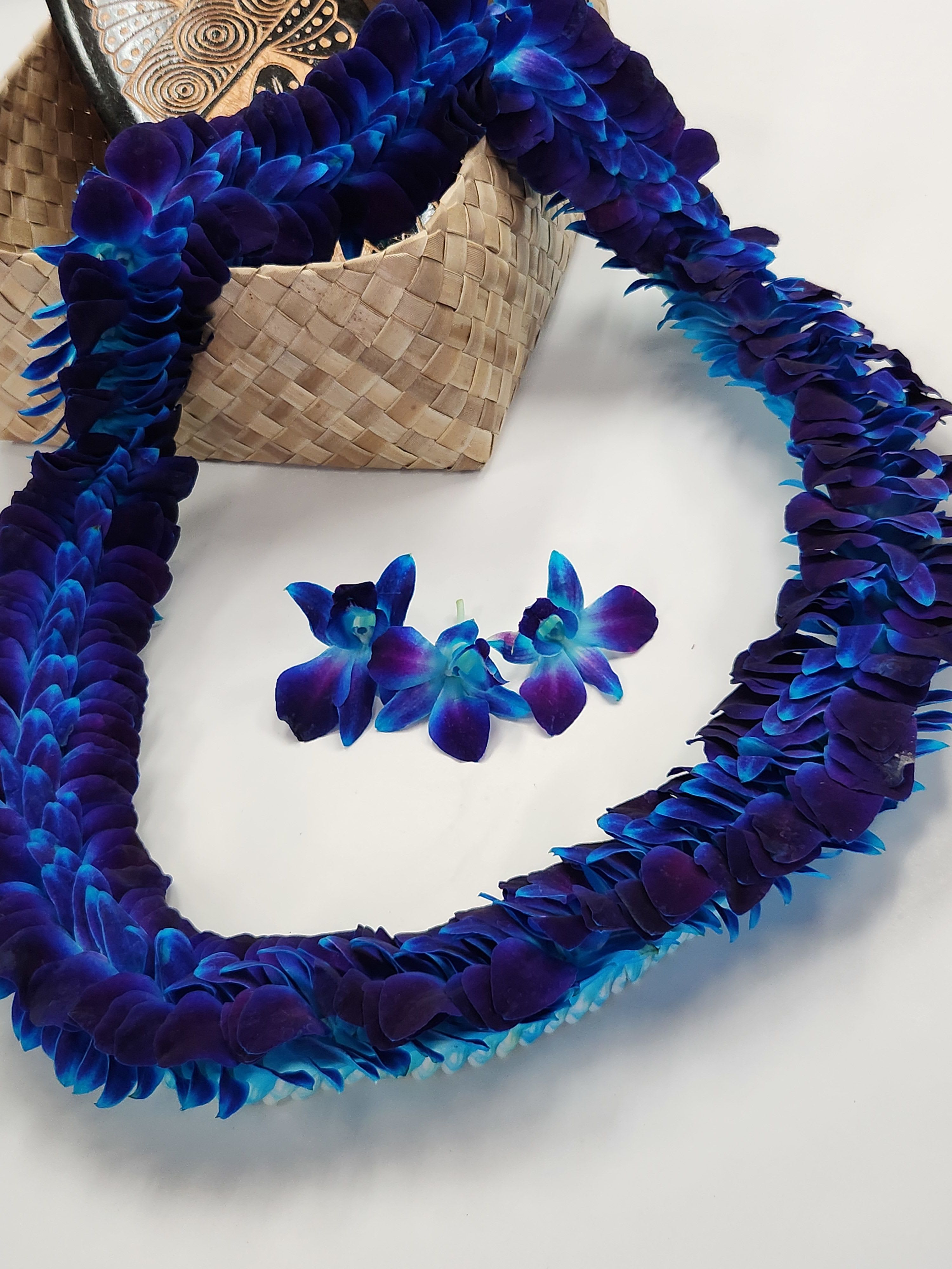 Blue-purple orchid lei with a woven basket and small orchid blooms