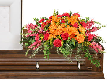 Bright orange and pink floral spray on a wooden casket