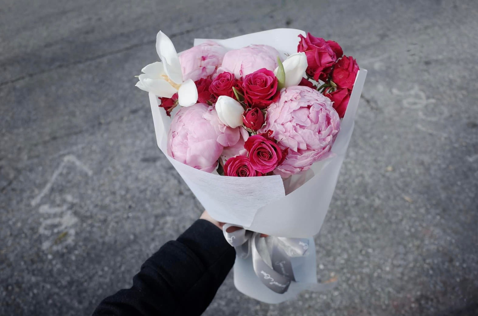 Velvet Peony Kiss - A luxurious symphony of elegance. Our Velvet Peony Kiss features premium crimson and blush peonies, symbolizing prosperity and romance. Artfully accented with white Phalaenopsis Orchids and wrapped in our signature "Cloud" style packaging.