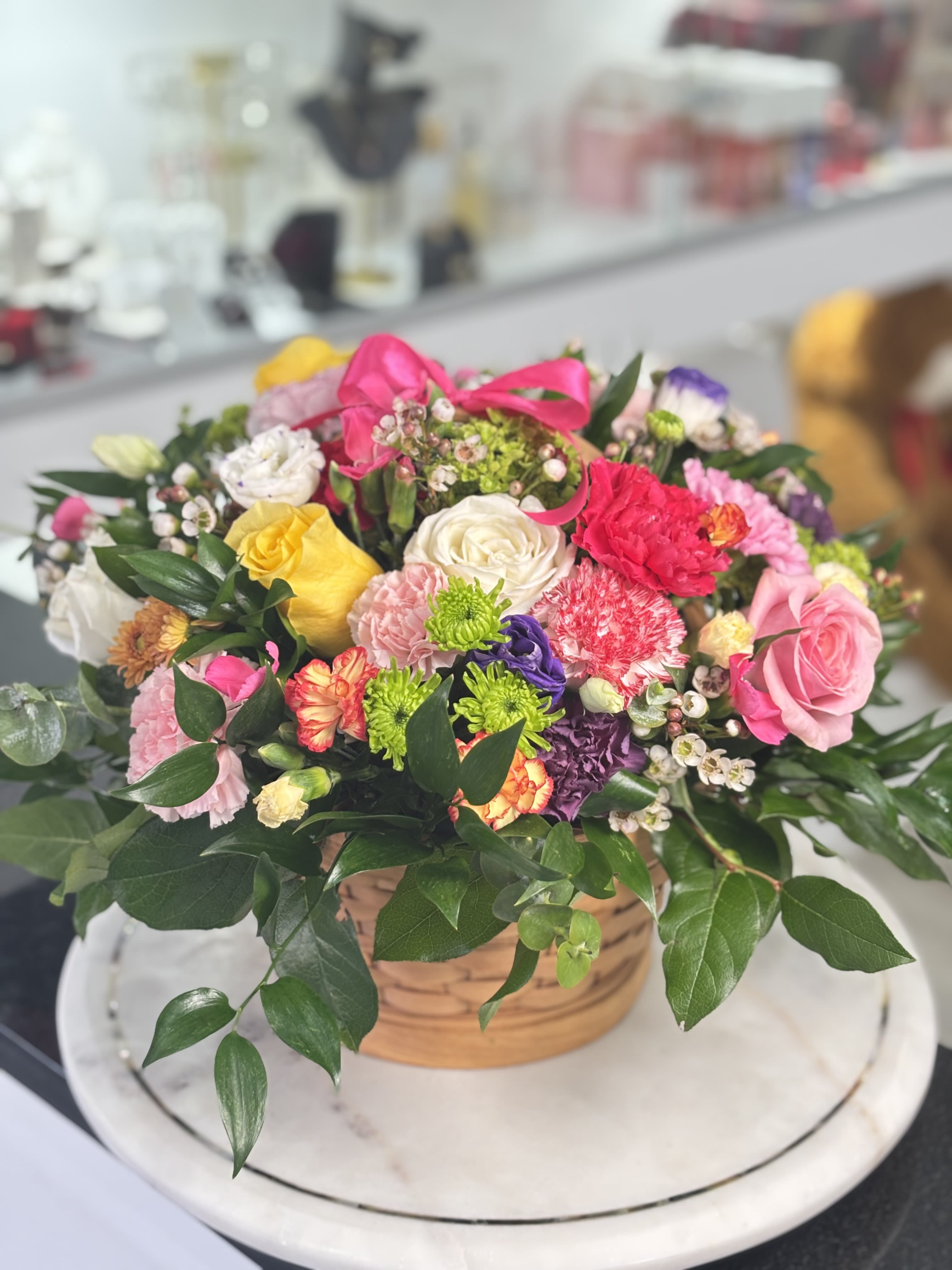 Mixed bouquet in a wicker basket with pink, yellow, white, and purple flowers