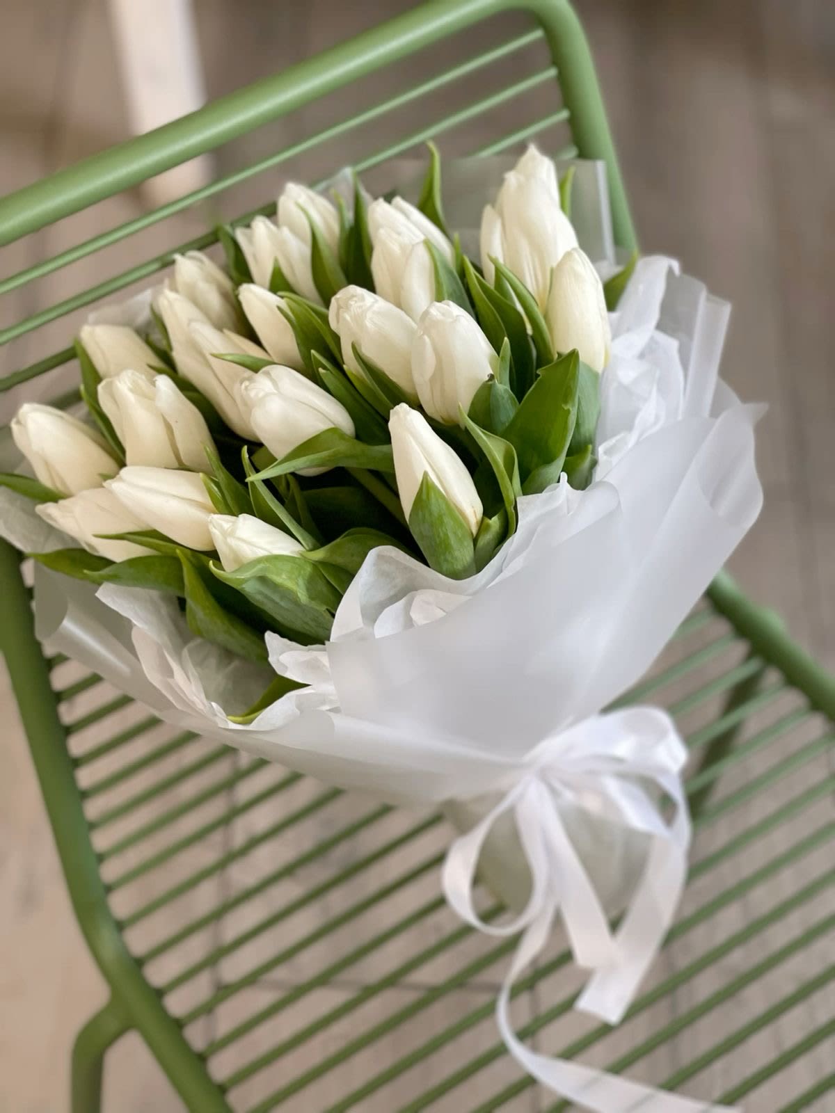 Bouquet of white tulips wrapped in white paper with a ribbon