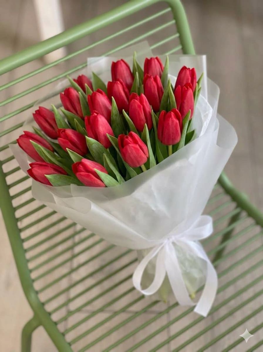 Bouquet of red tulips wrapped in white paper with a ribbon