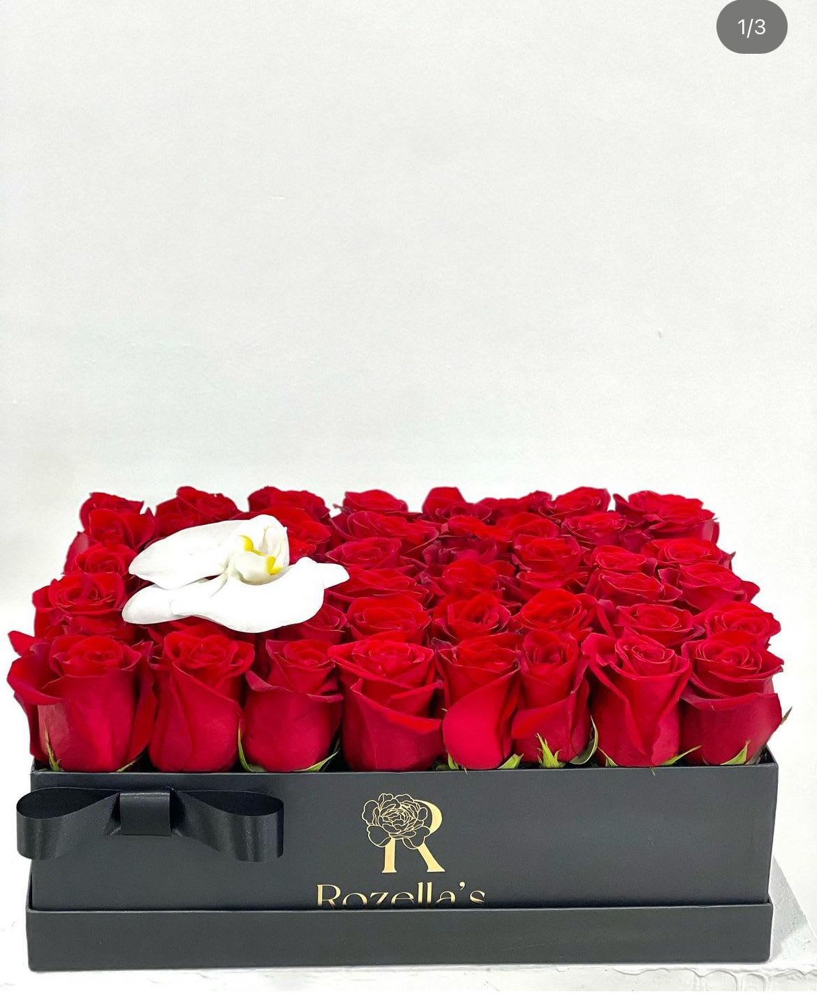 Box of red roses with a white orchid accent