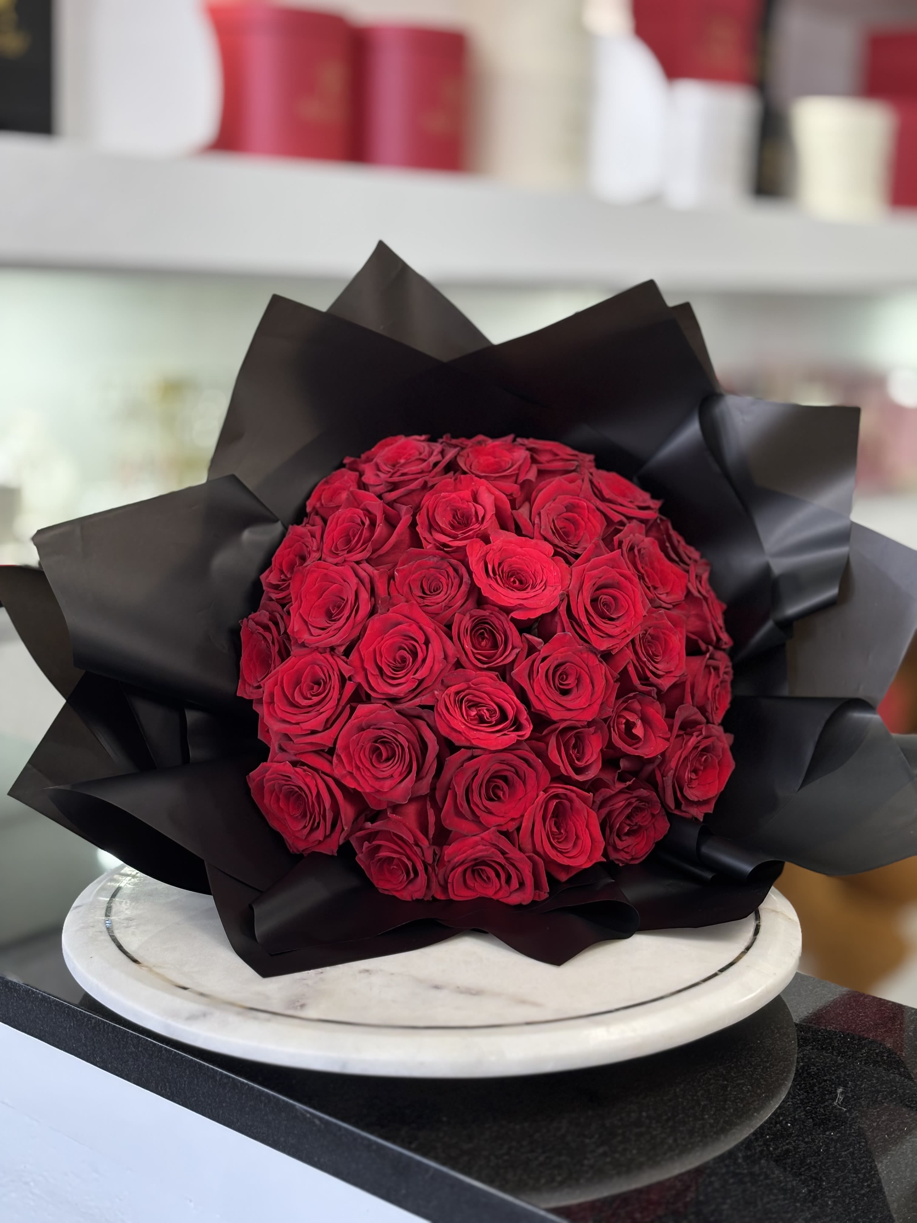Round bouquet of red roses wrapped in black paper