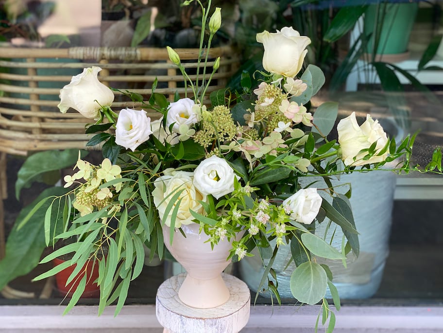 White roses and small white blooms in a pale vase