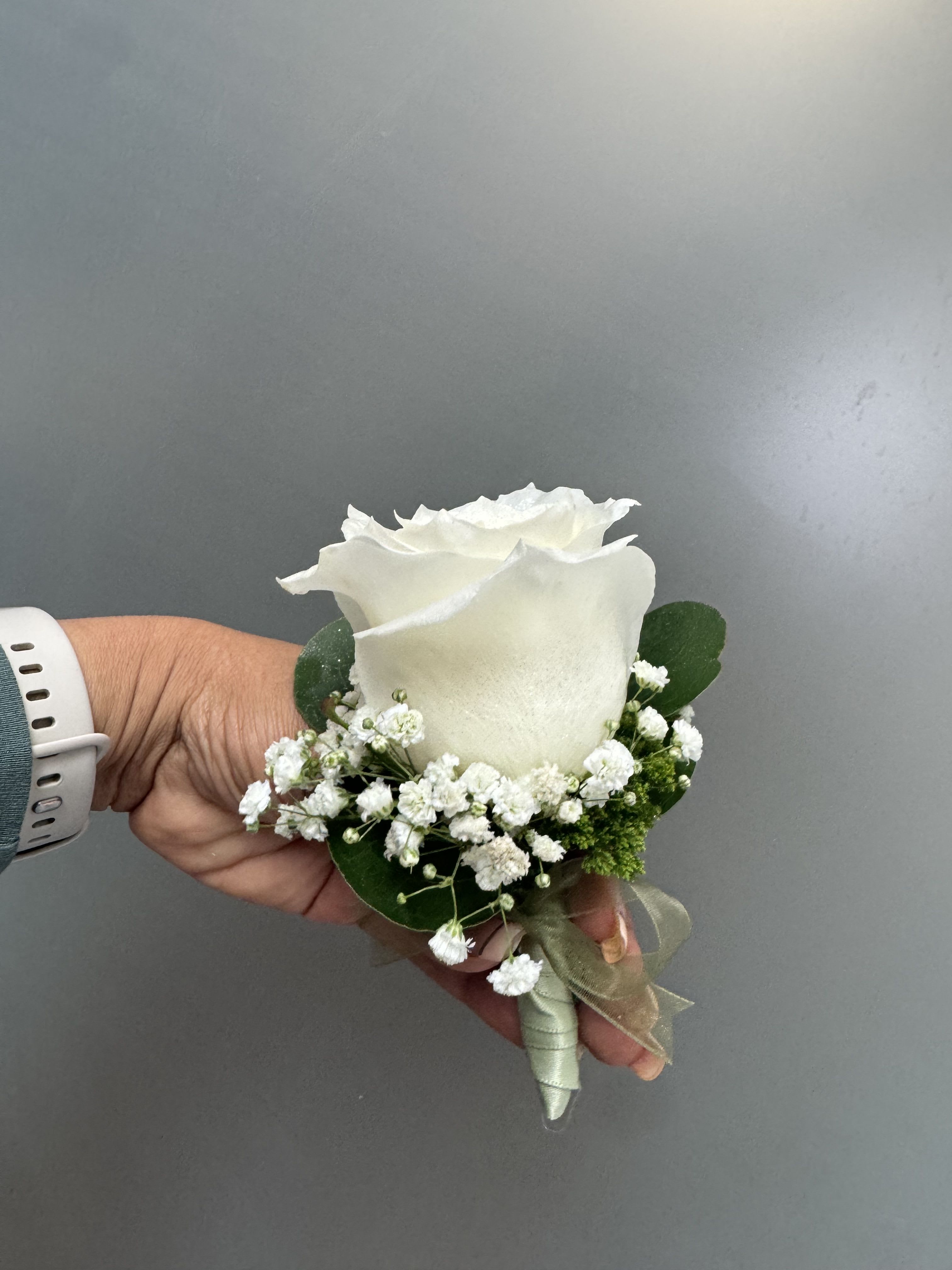 White rose boutonniere with baby's breath and green ribbon