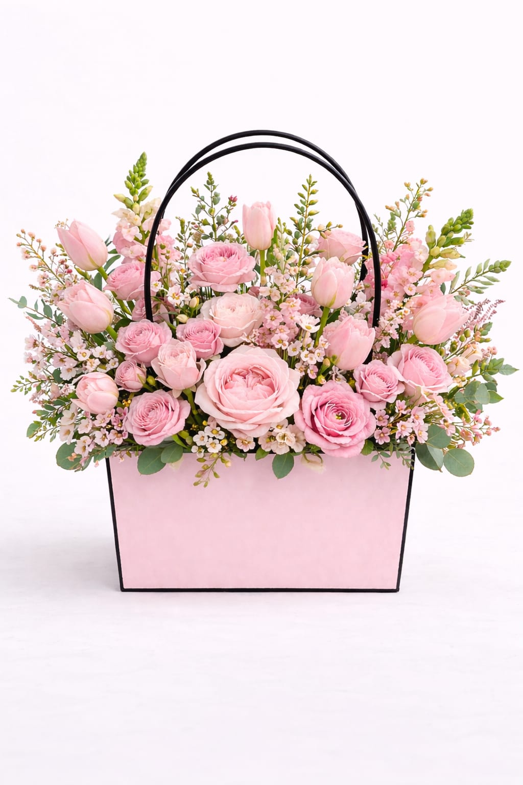 Morning Blush  - a soft garden -style arrangement in delicate shades of pink featuring roses, tulips, seasonal blooms, and airy greenery in our signature floral tote. Romantic, elegant, and timeless.