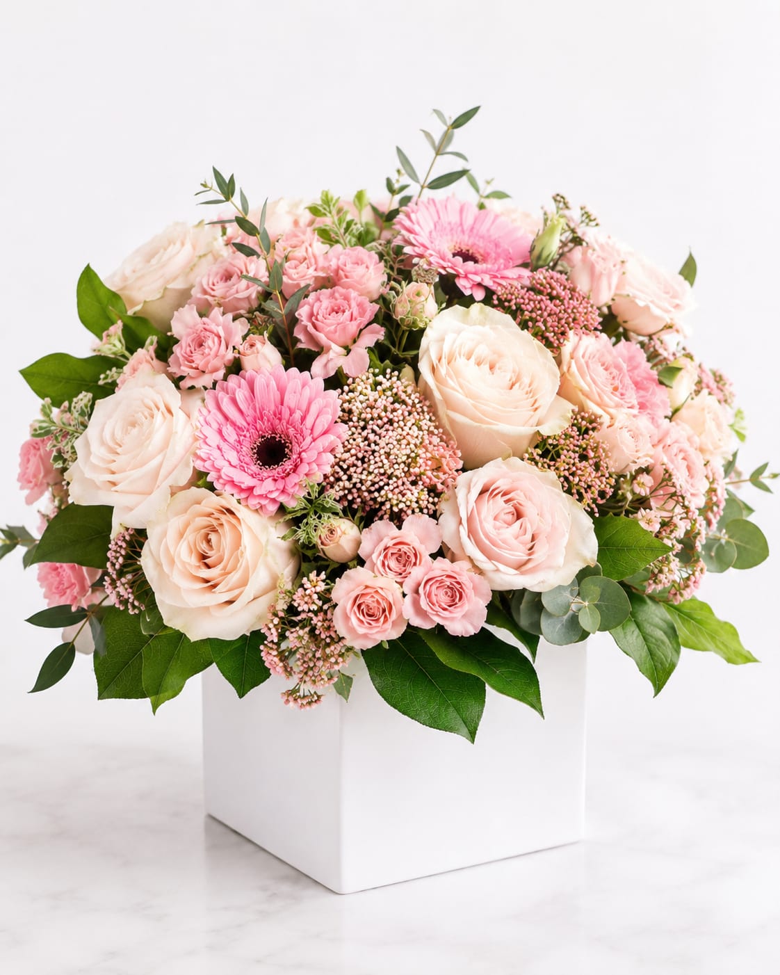ballet slipper  - an elegant arrangement designed in a modern white cube vase featuring soft blush roses, daisies, seasonal blooms, and fresh greenery. Airy ,feminine, and full of gentle garden charm, this arrangement brings a timeless touch of sweetness and elegance to any space .
