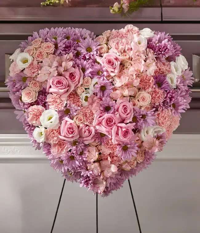 Heart-shaped floral arrangement of pink and lavender flowers on a stand