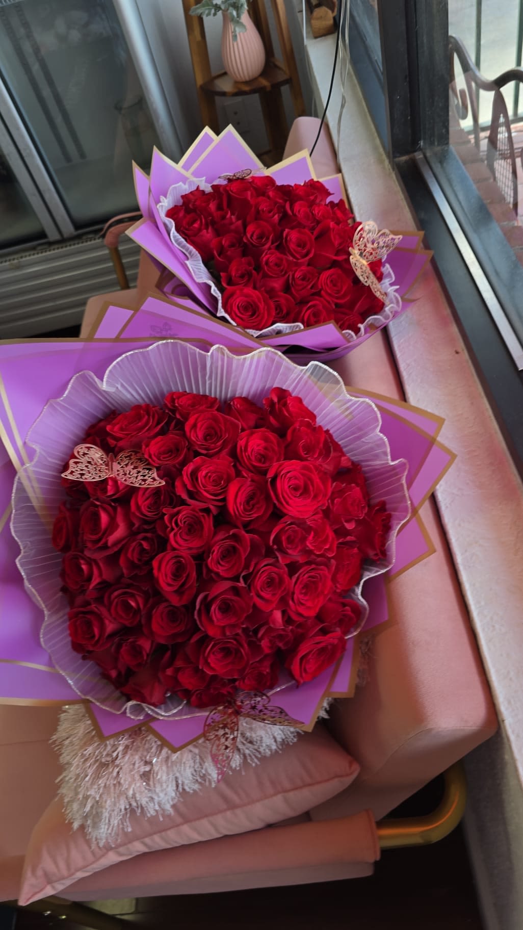 Two bouquets of red roses wrapped in purple paper