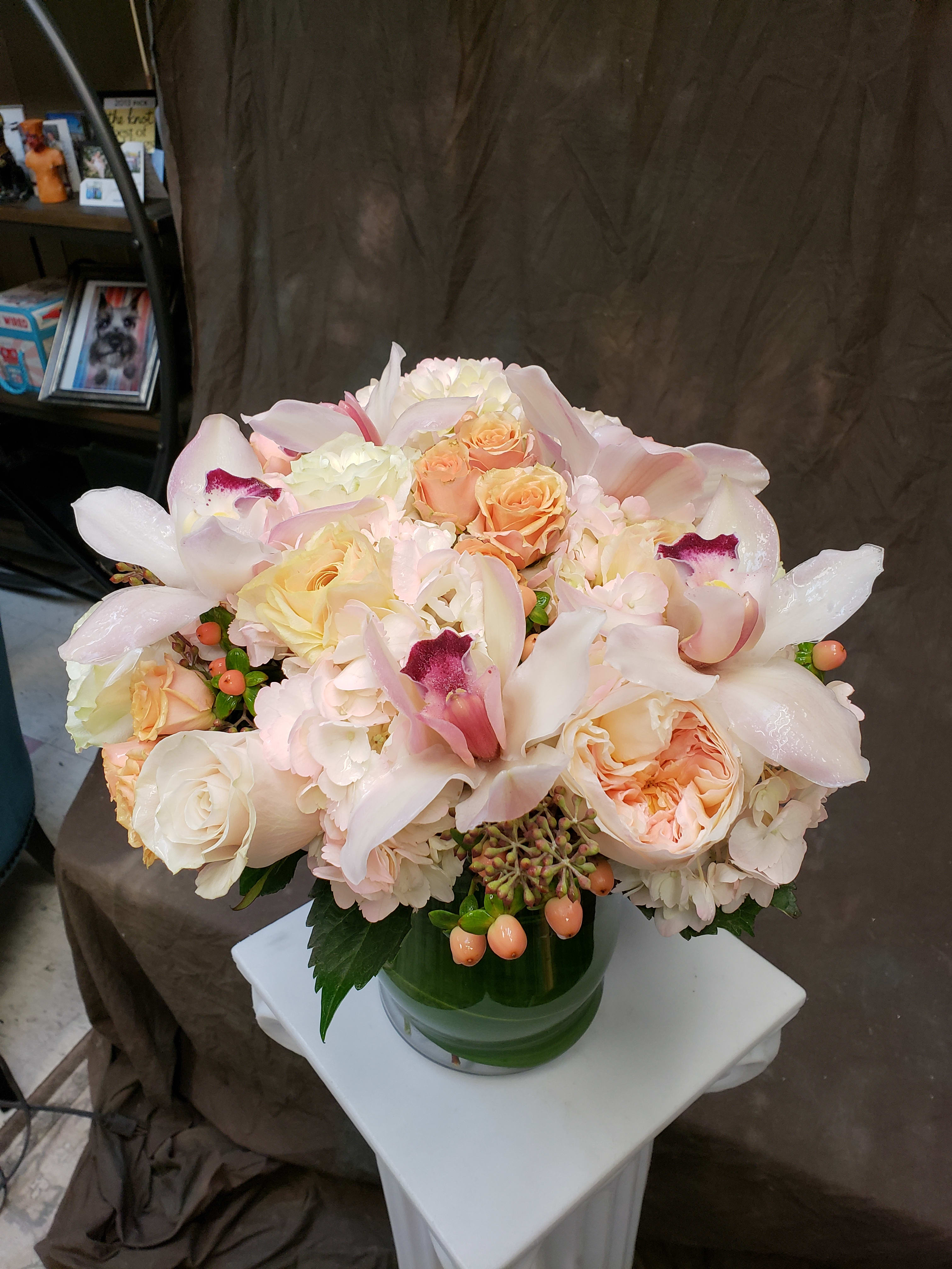 Blush and cream bouquet with roses and orchids in a glass vase