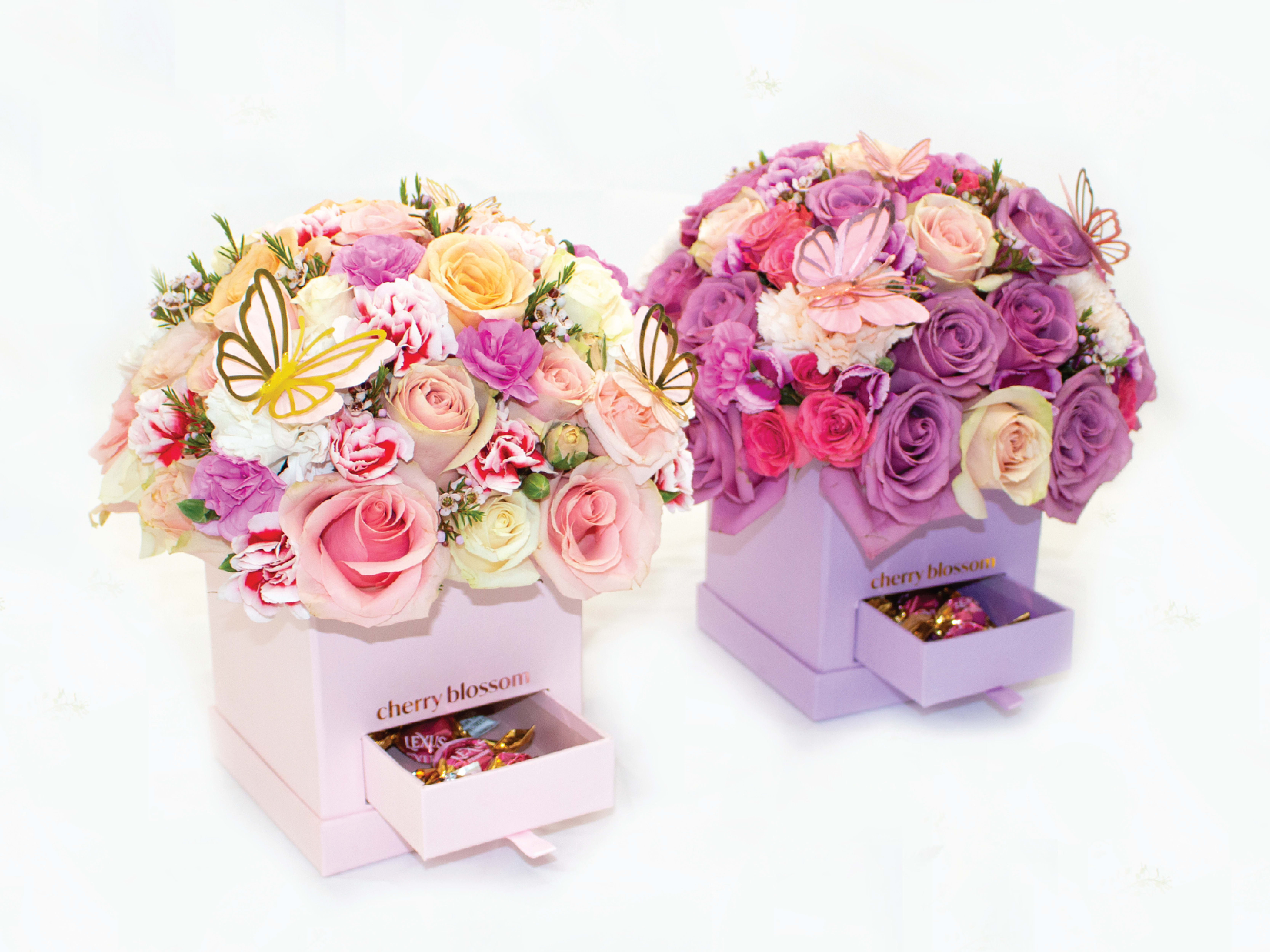 Two pastel flower boxes with roses and butterfly decorations