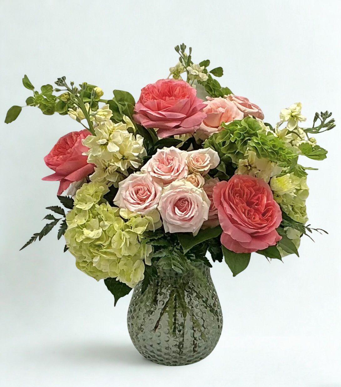 Pink roses and green hydrangeas in a textured glass vase